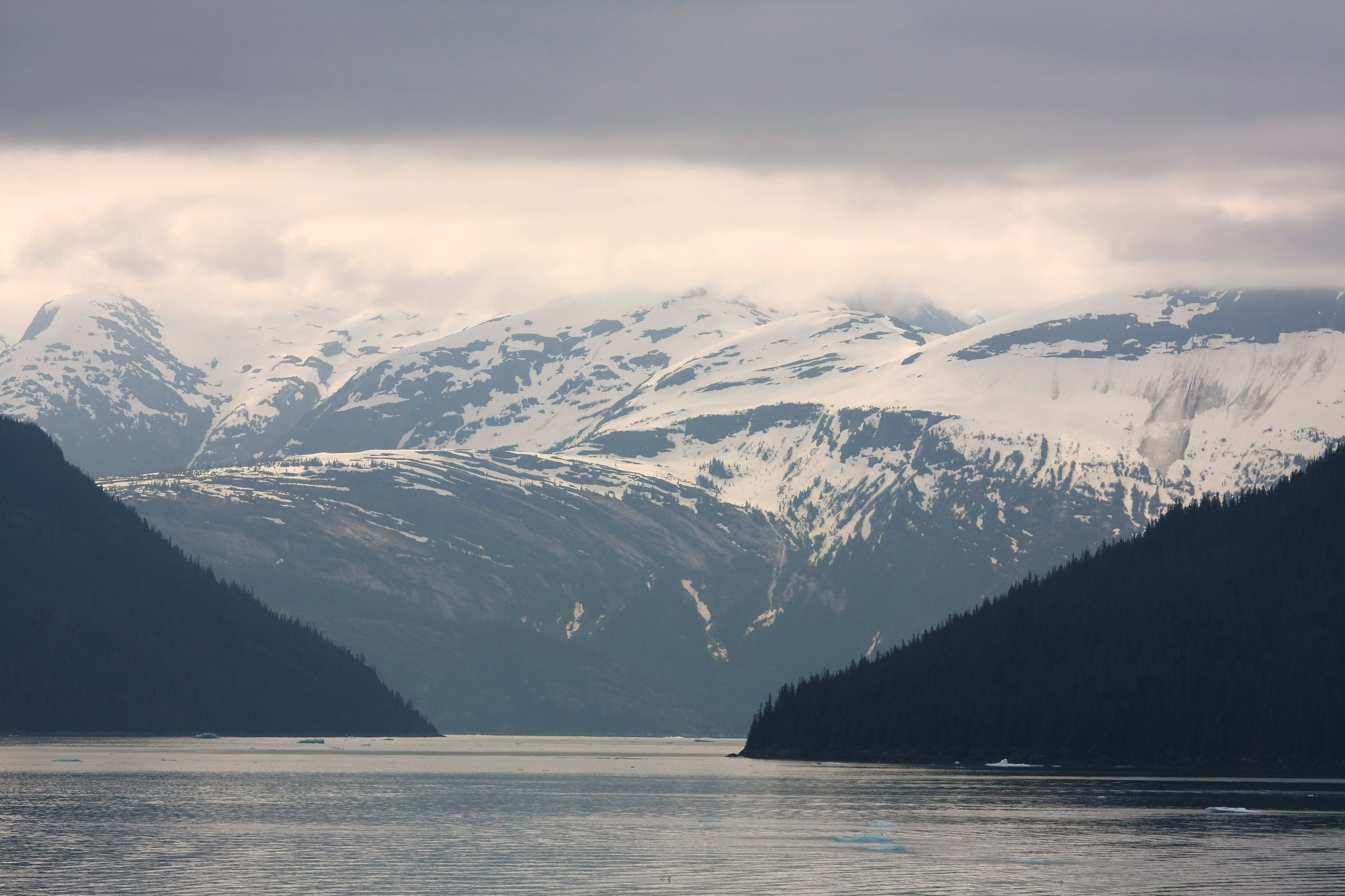 V-shaped fjord gate opening to distant snow-capped peaks.