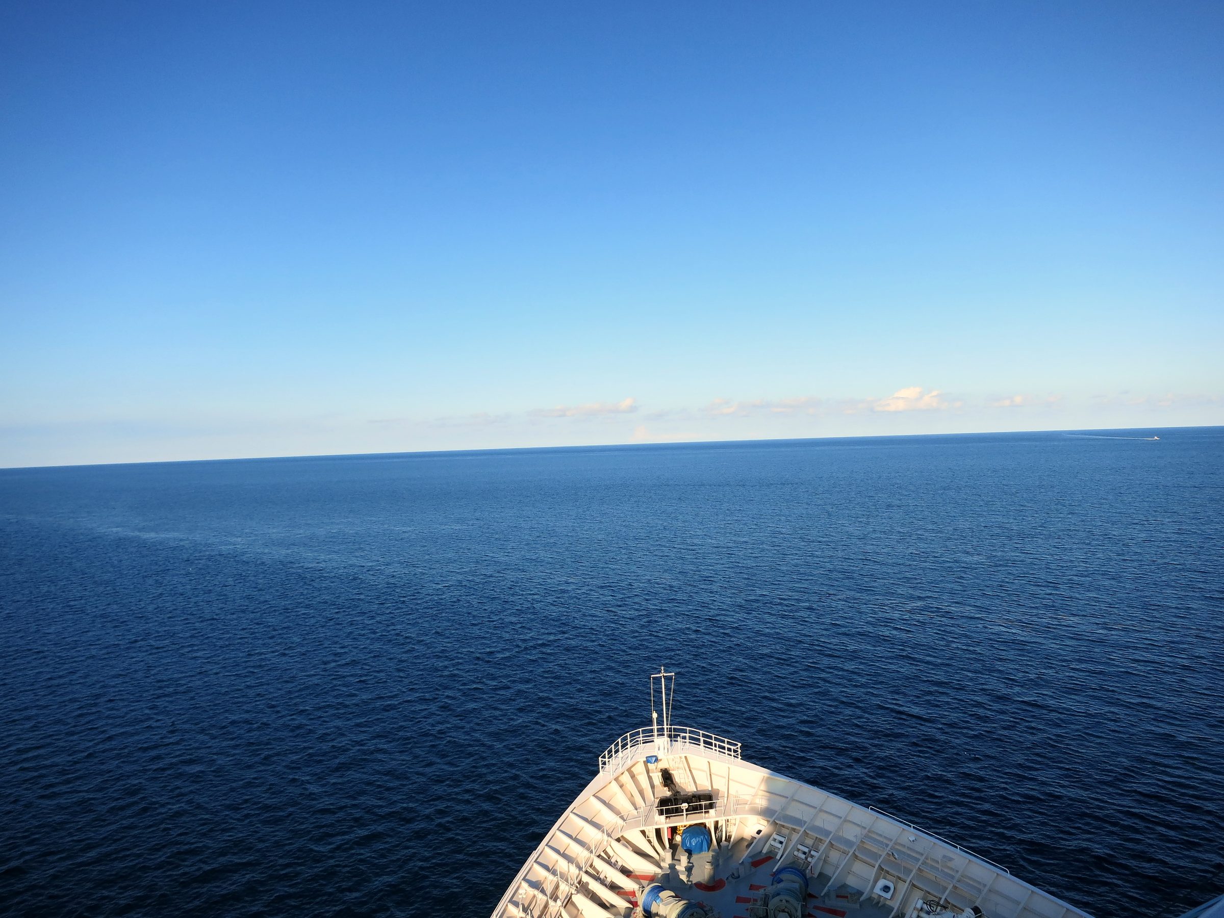 Ship bow railing pointing at empty blue horizon.