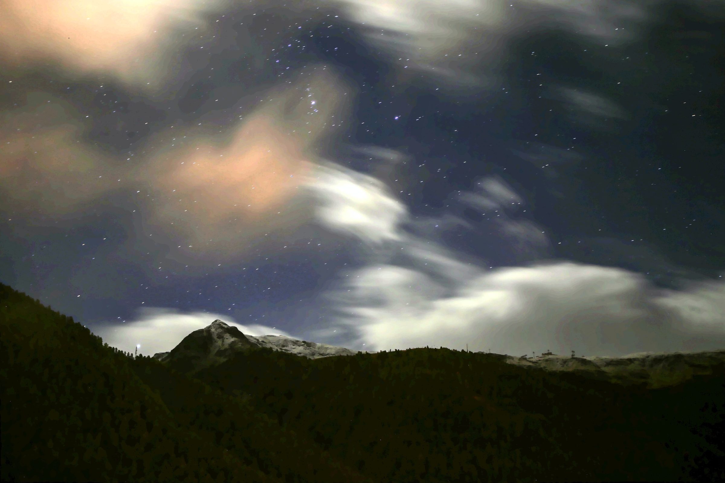 Night ridge under stars with a faint warm band over the snow.