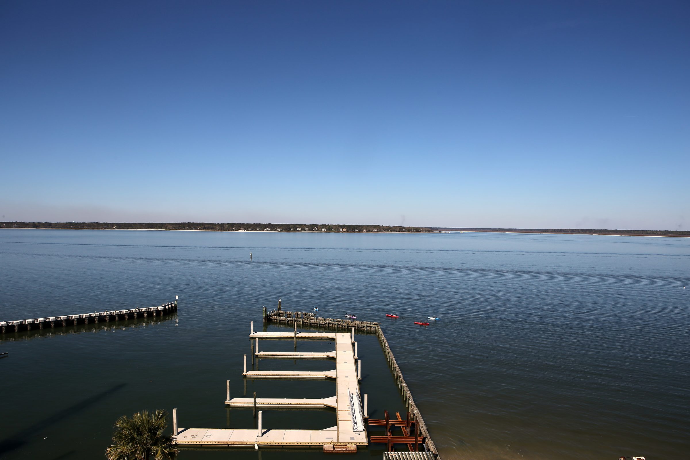 High wooden pier over calm blue bay under clear sky.