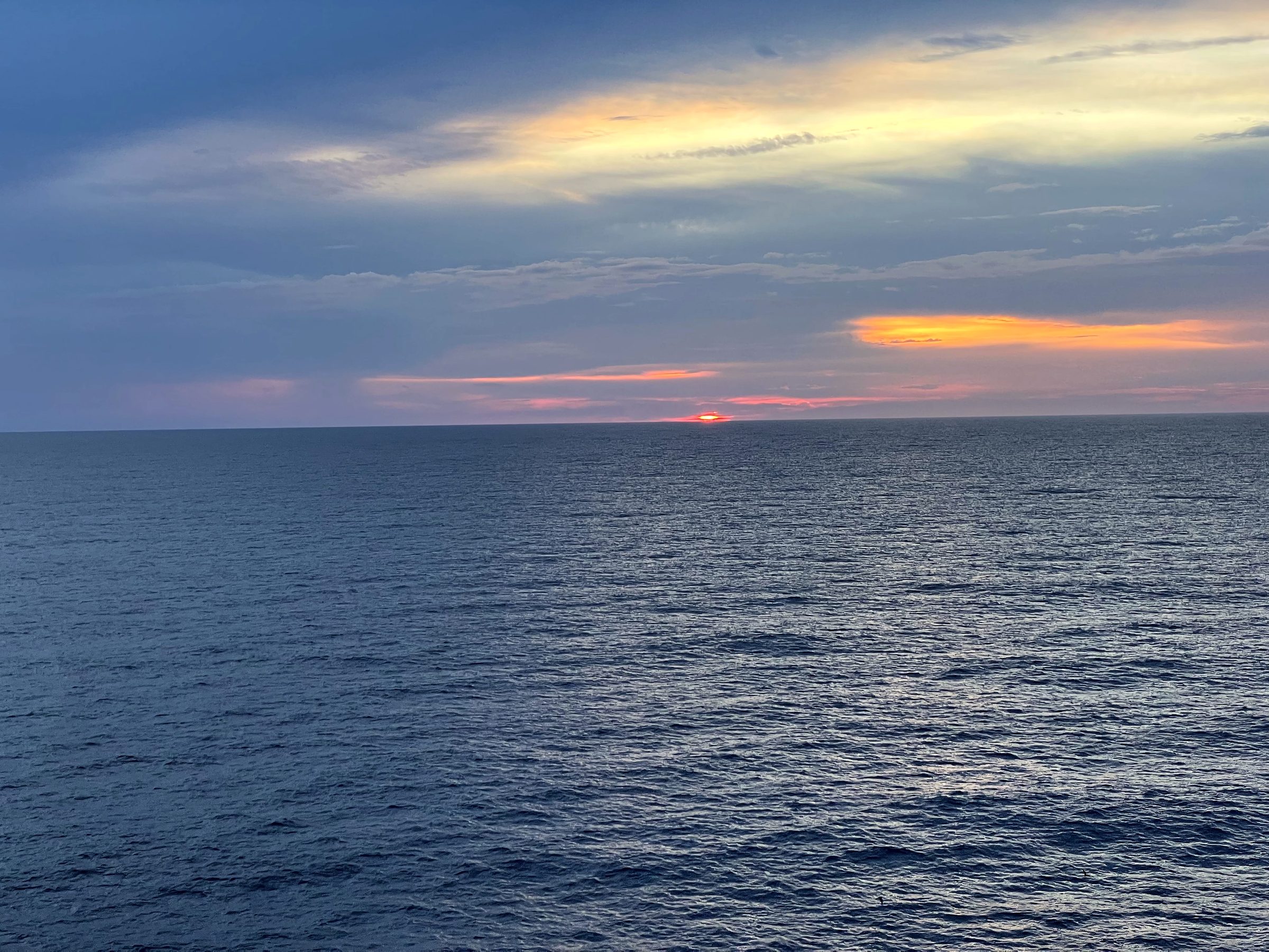 Vast dark blue sea with a thin ember of light on the horizon.