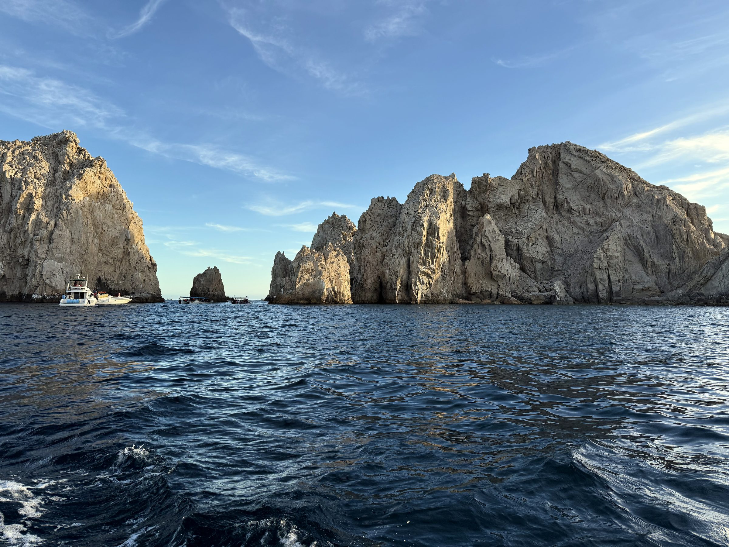 Yacht near towering tan cliffs at Cabo's land's end.