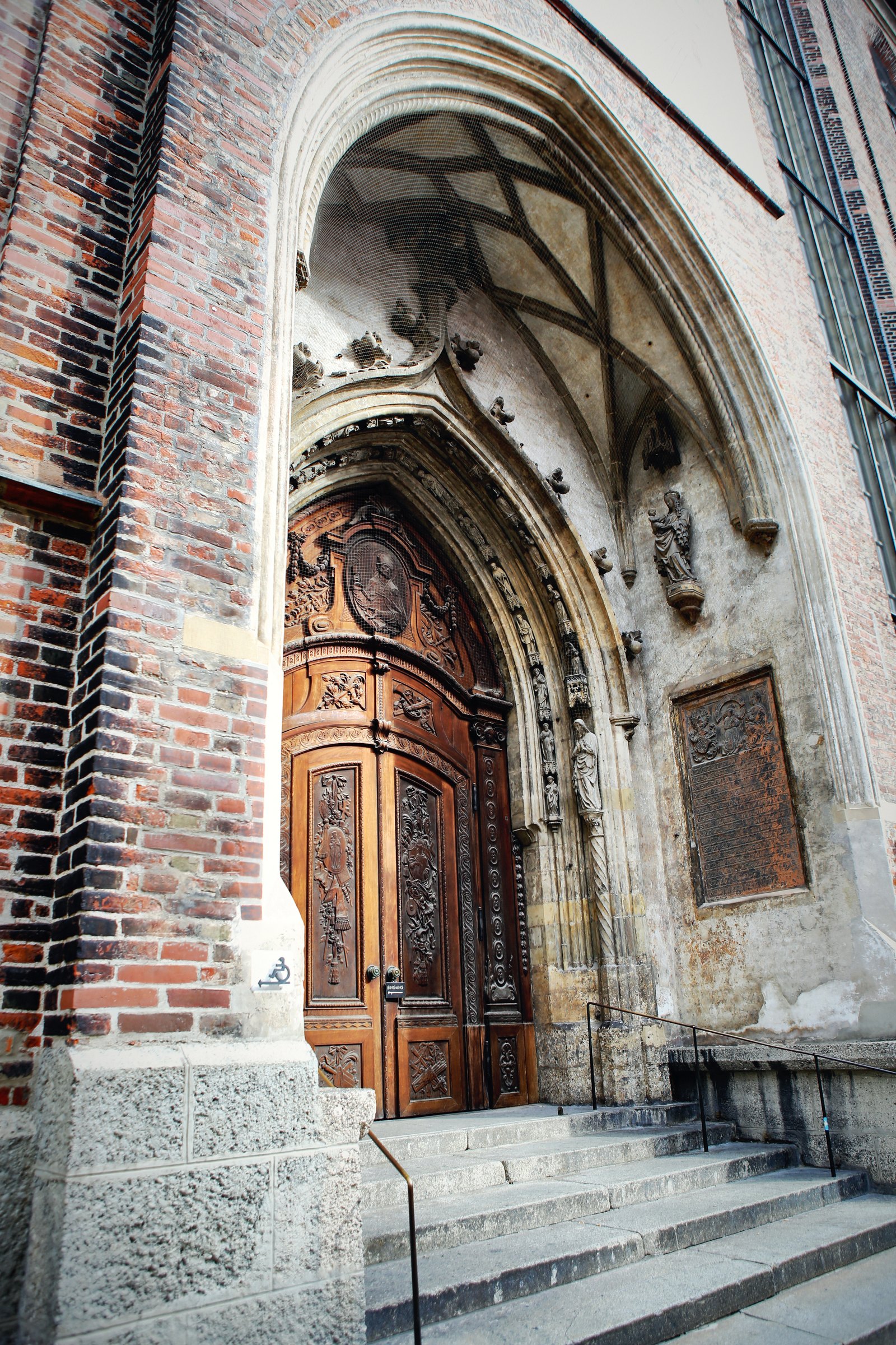 A carved stone Gothic doorway set into a brick church, steps leading up.