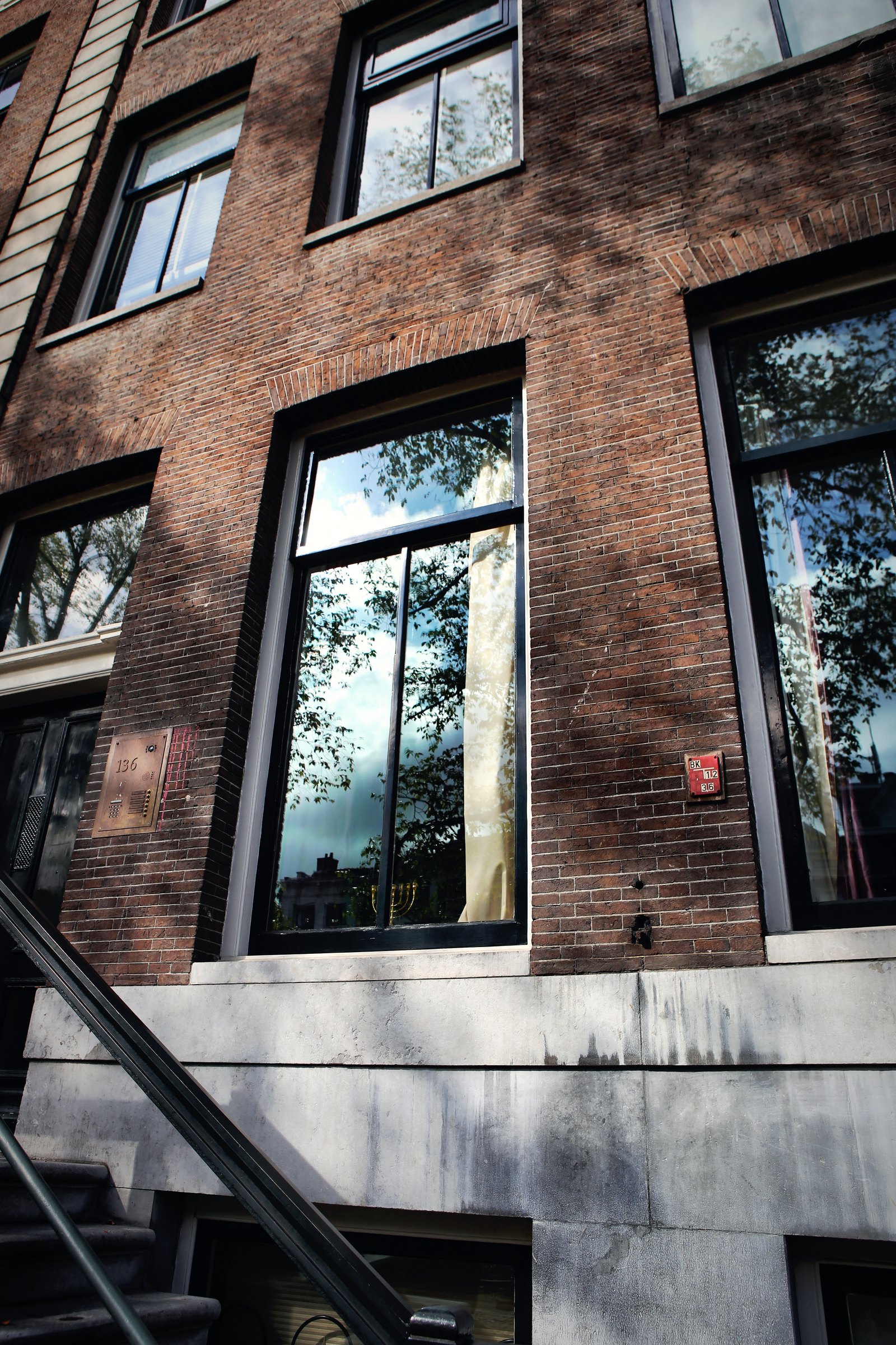 A brown brick facade with tall black-framed windows and an iron railing.
