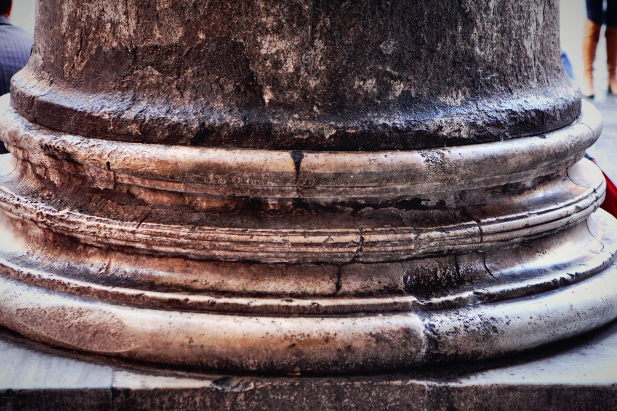 The worn stone base of a massive column, close up.