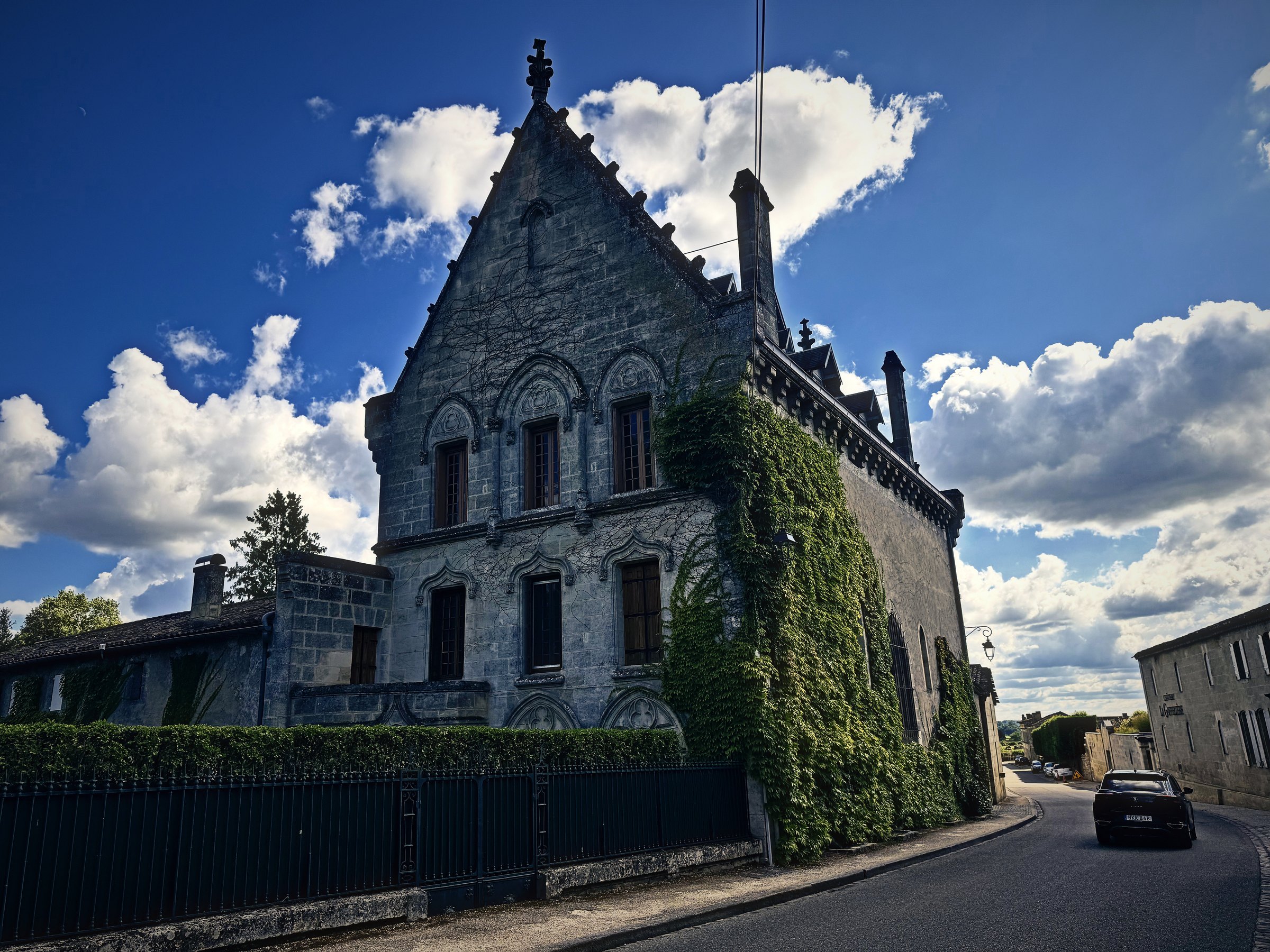 A steep-gabled Gothic house wrapped in ivy, set against blue sky and towering white clouds.