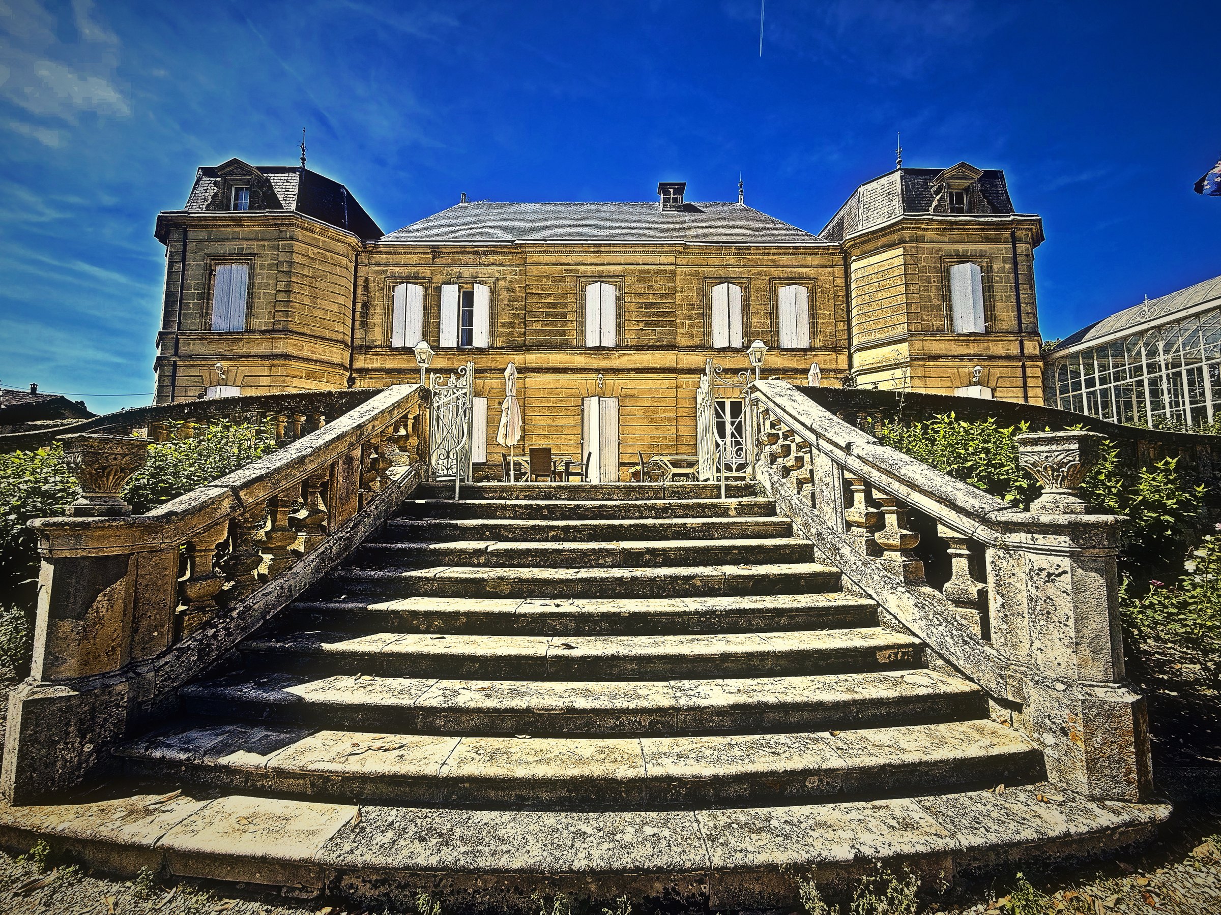 A grand double flight of stone steps rising to a pale château under a deep blue sky.