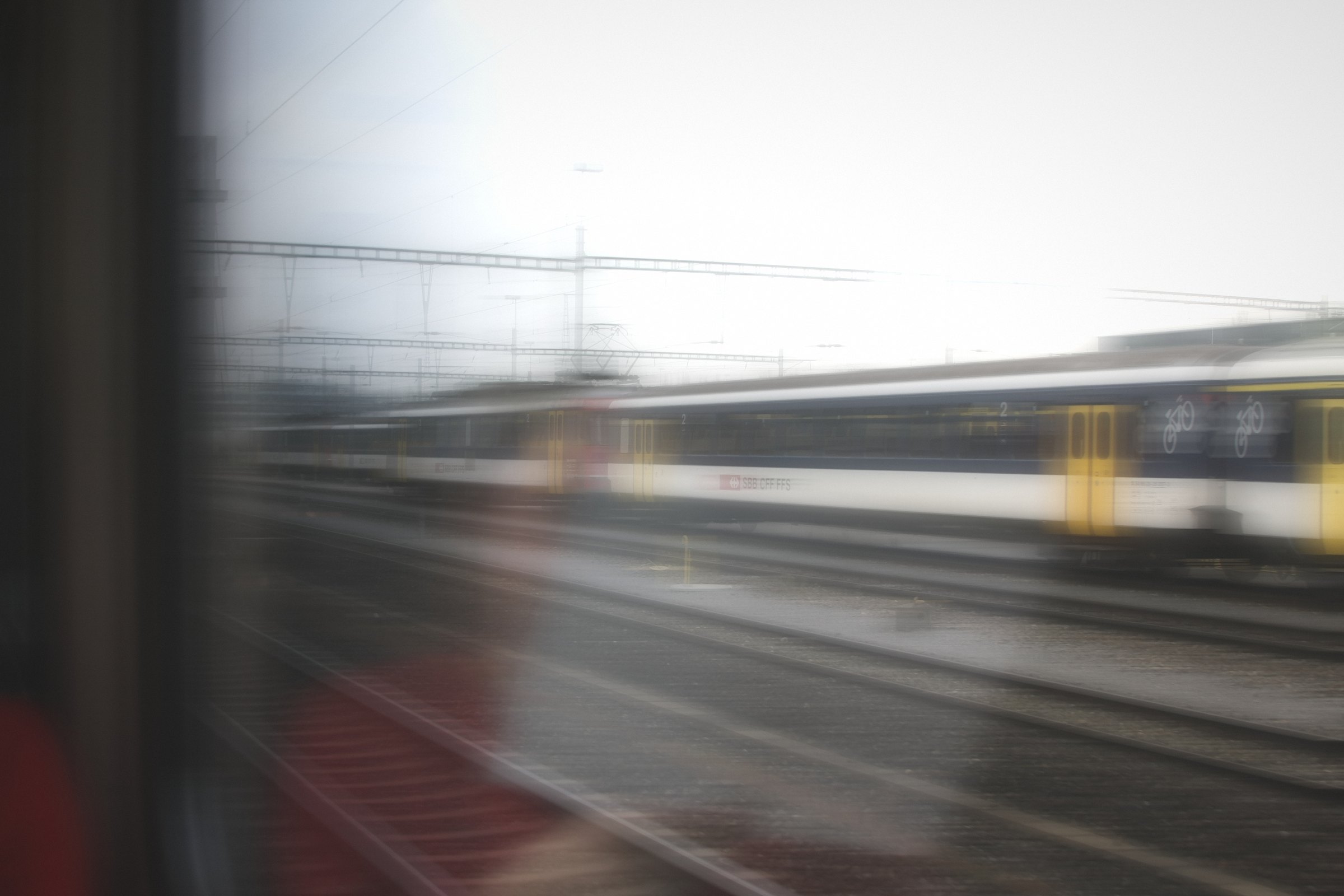 Soft, pale blur of a passing train seen through a carriage window.