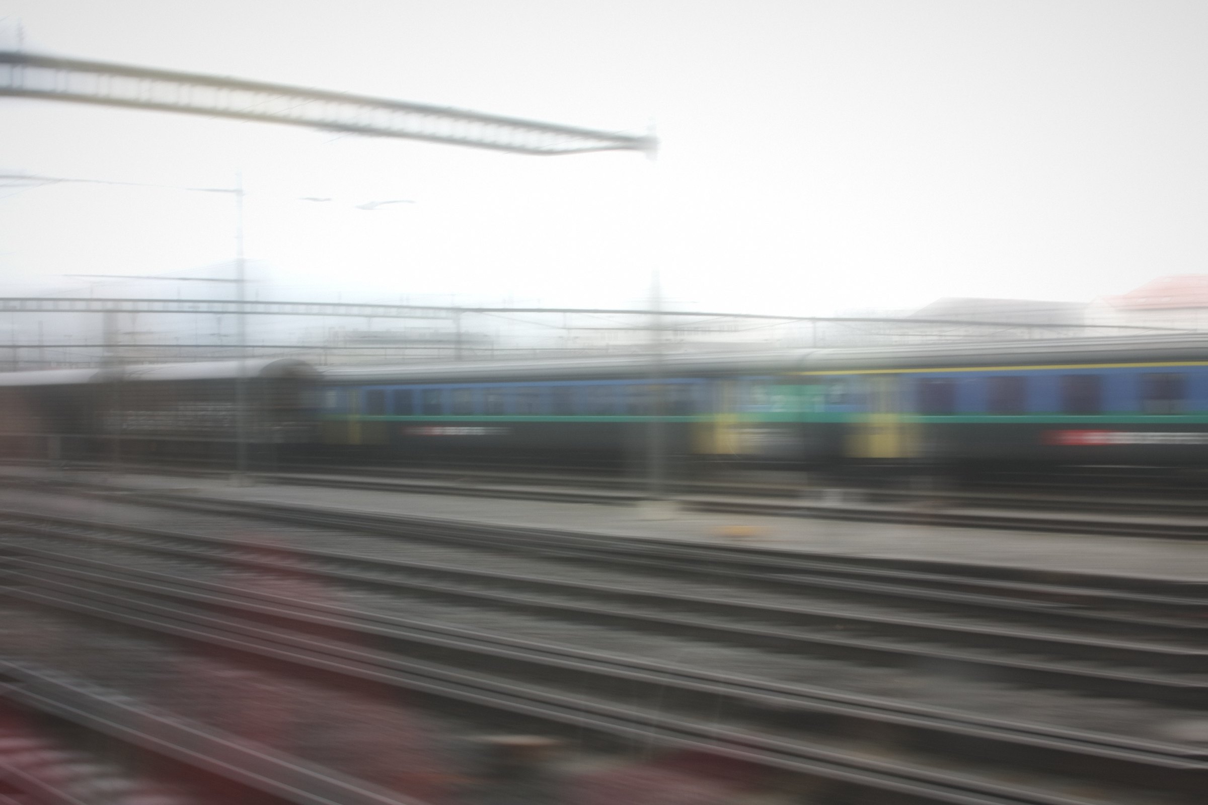 Pale horizontal blur of blue and yellow coaches beside the tracks.