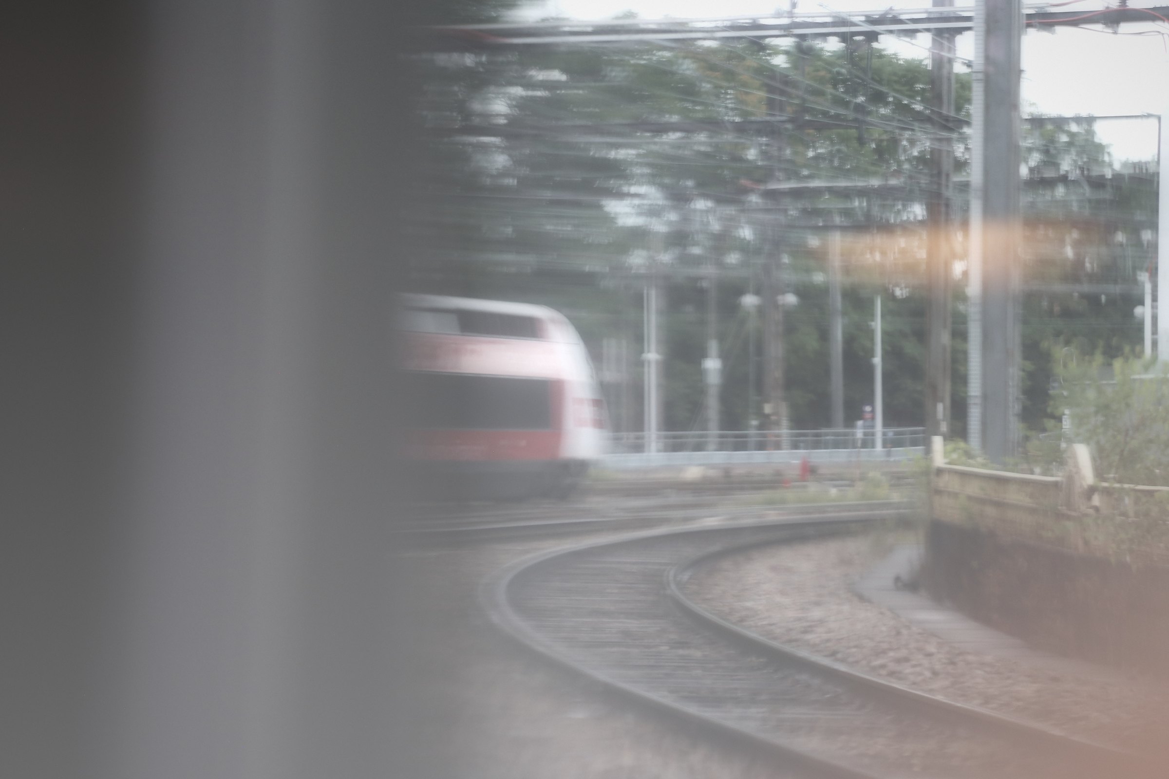 Dreamy view of a red train front rounding a curve, framed by a window edge.