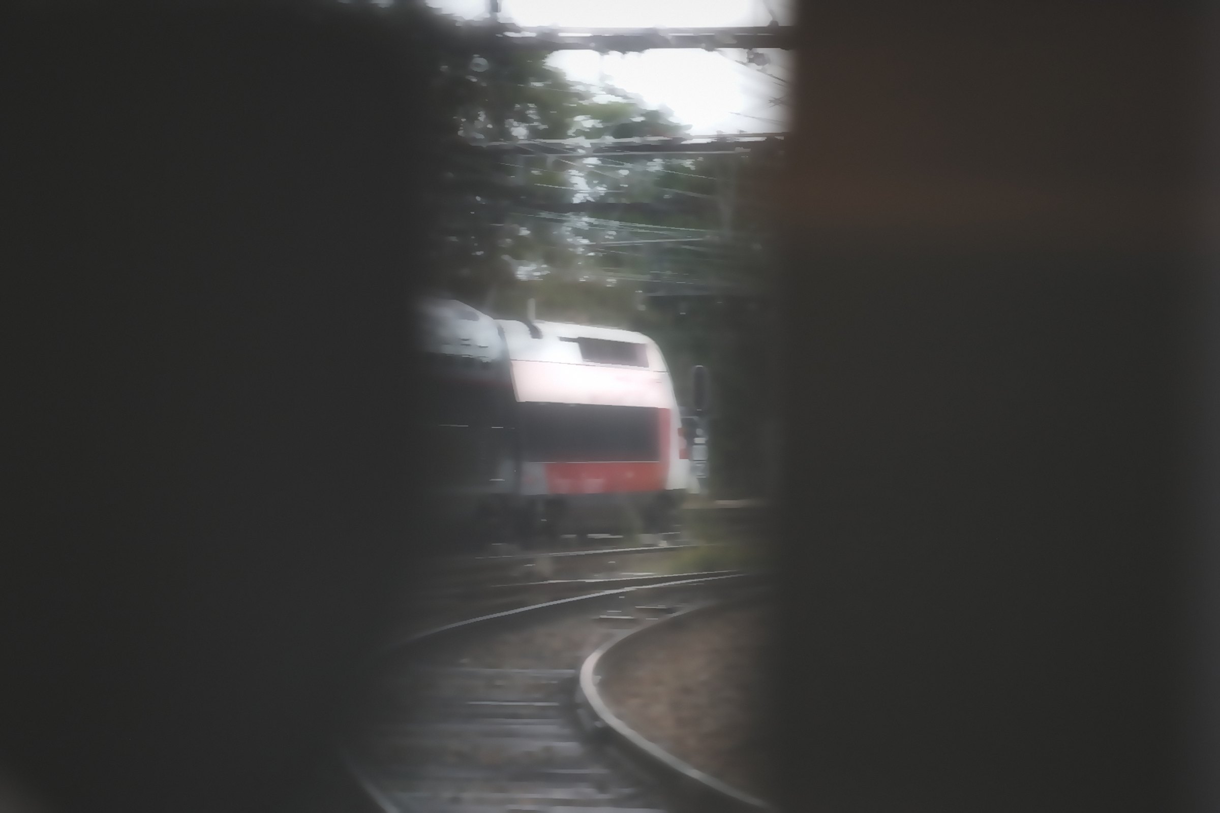 Dark window frame on both sides with a red train glowing in the curve between.