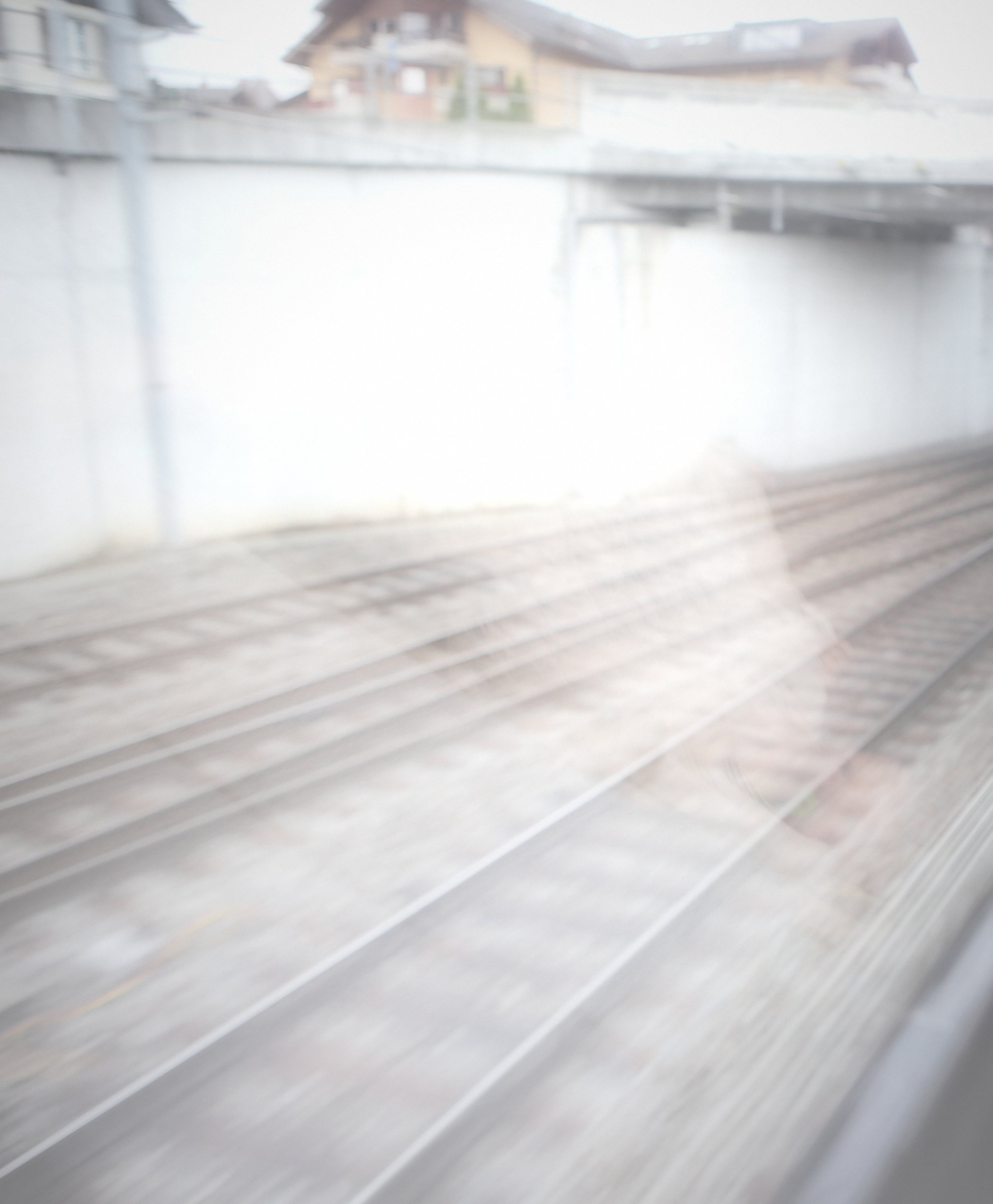 Bright mist falling across tracks below a concrete wall.