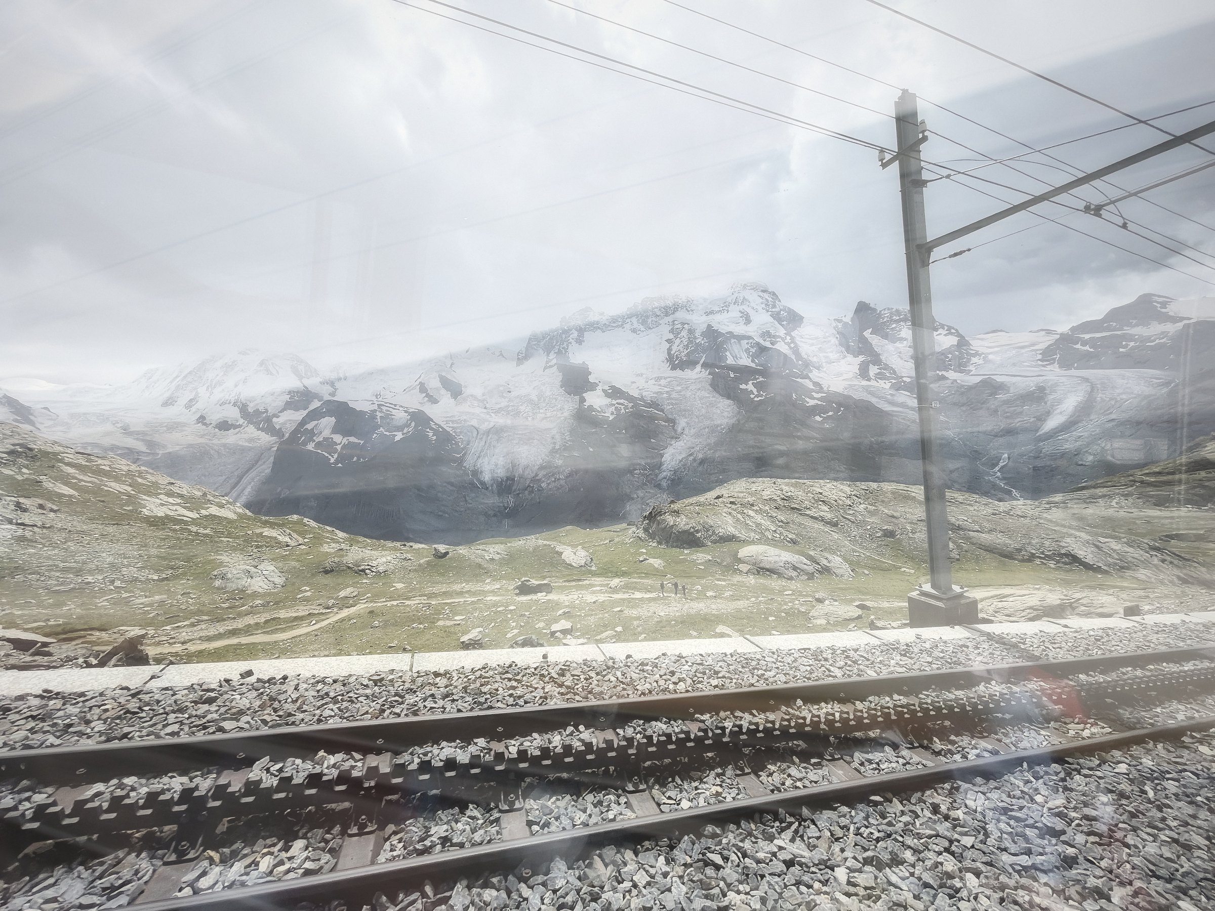 Double exposure of snowy peaks and railway tracks in pale light.