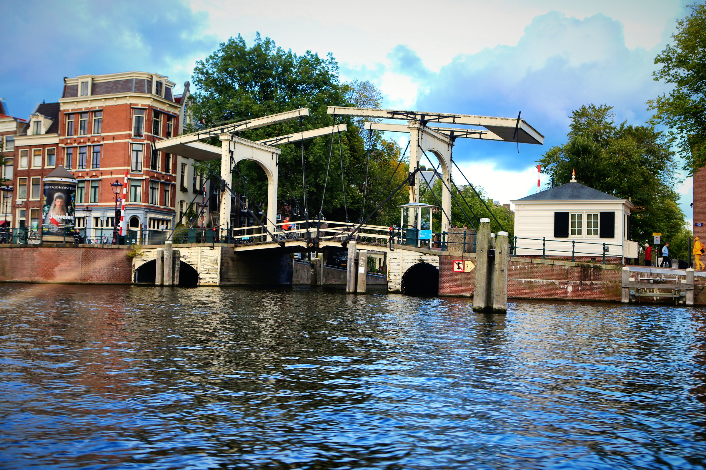 A white wooden drawbridge spanning a canal between brick houses.
