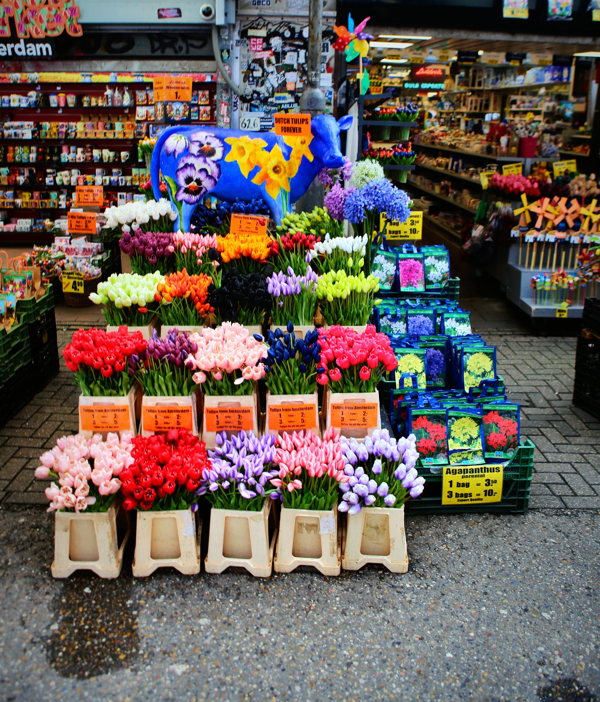 Buckets of bright tulips and mixed flowers stacked on a market stall.