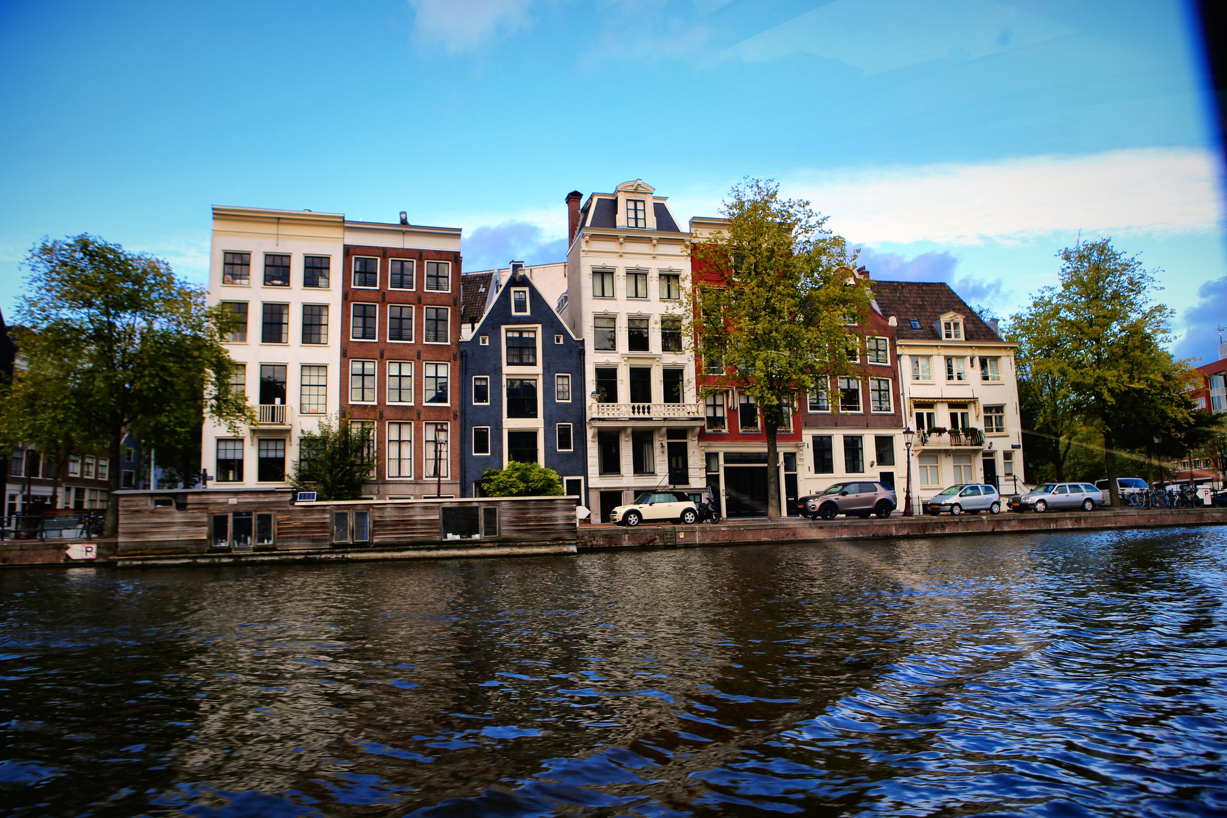 A row of canal houses with different gables seen from the water.