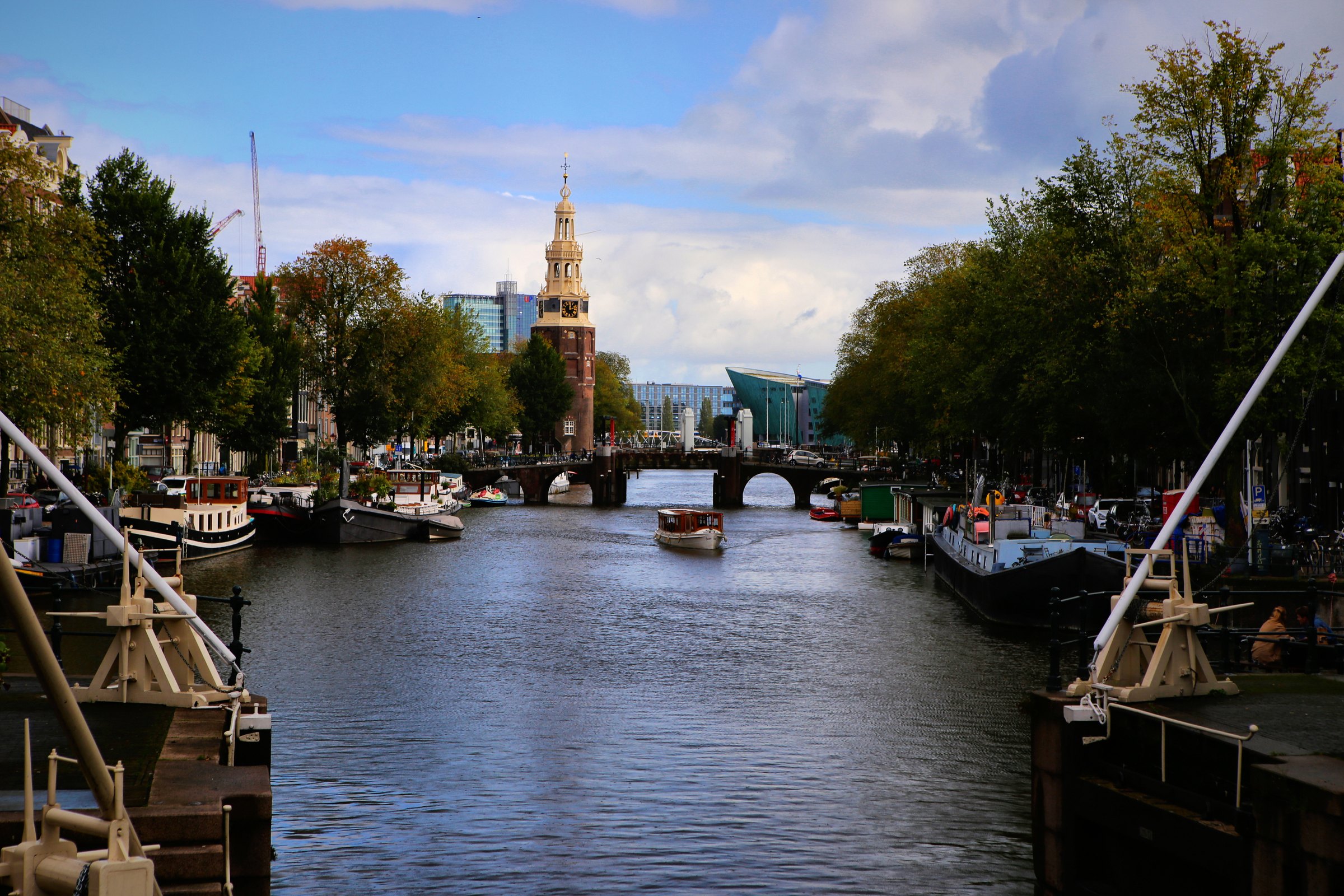 A canal leading to a distant clock tower, framed by moored boats.