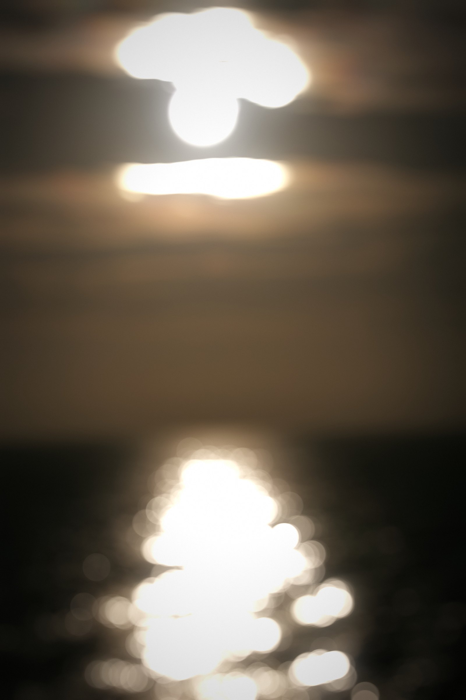 Bright sun reflection breaking into sparkling orbs on dark water.