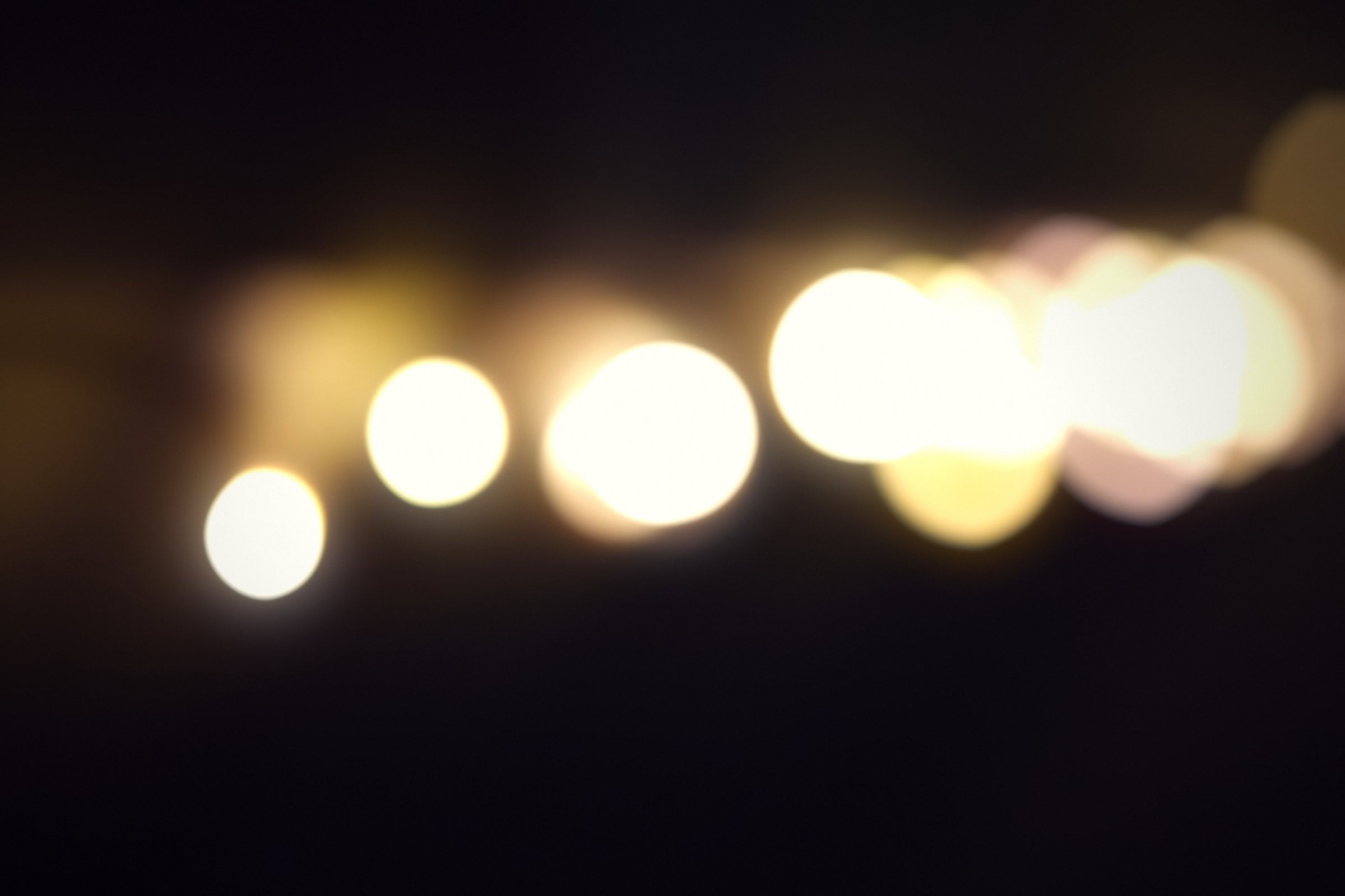 A row of warm lights dissolved into soft gold circles on black.