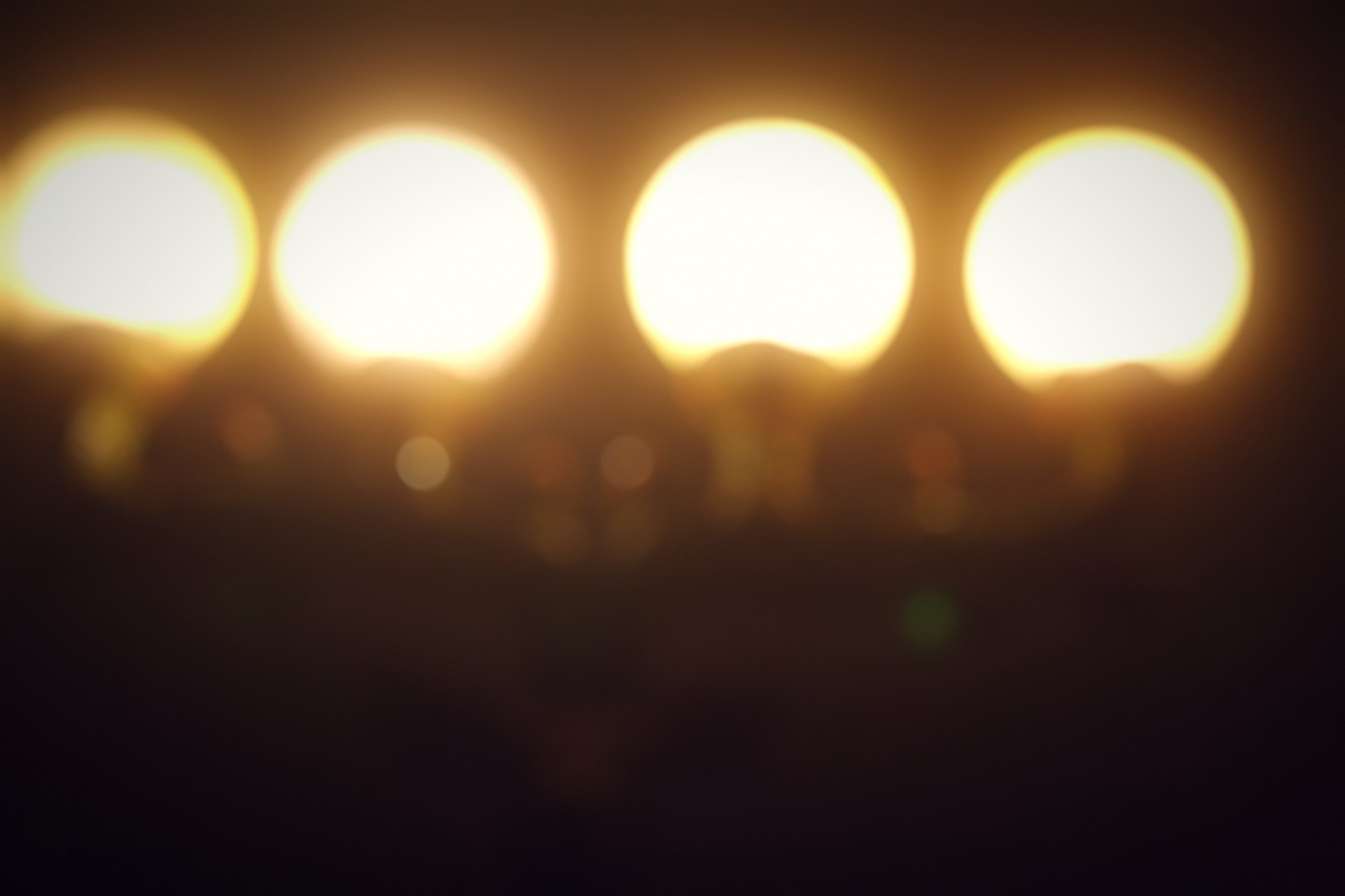 Four large glowing globes in a row against a dark background.