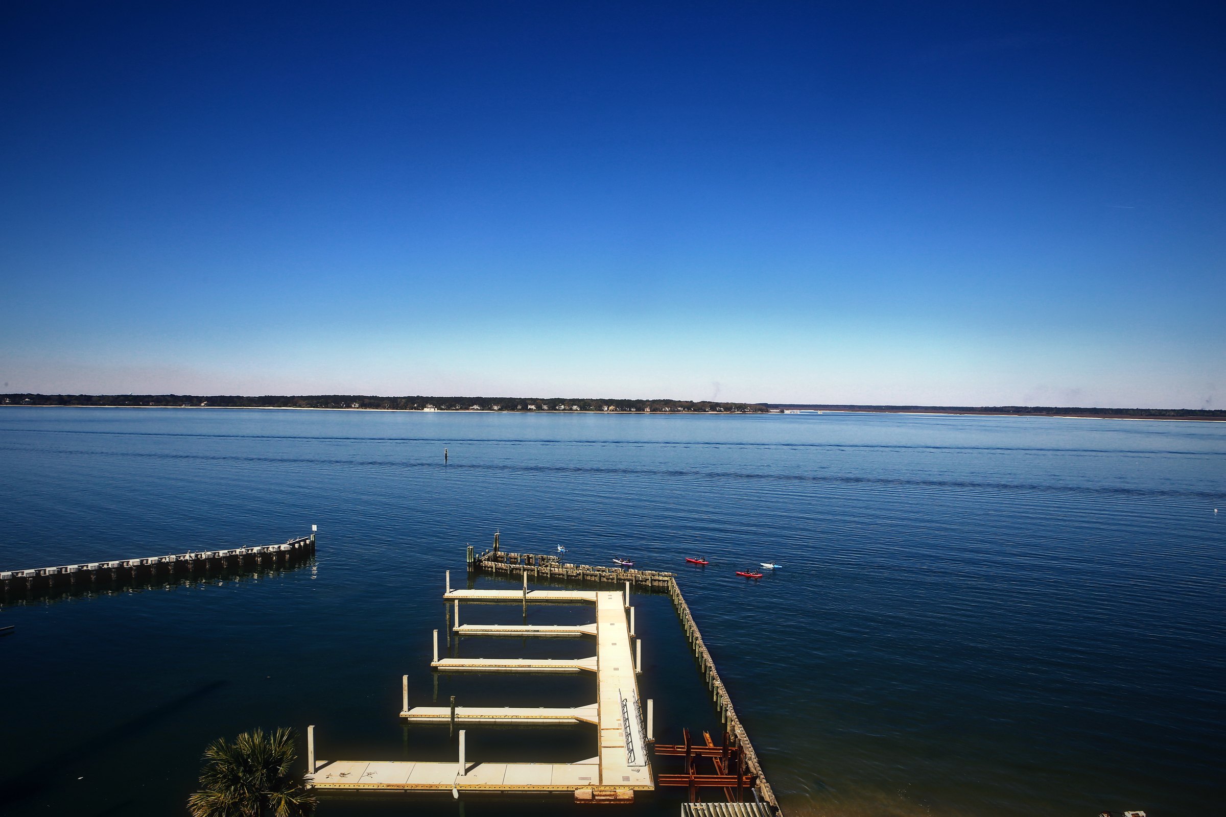 Empty floating dock slips on calm blue water under a clear gradient sky.