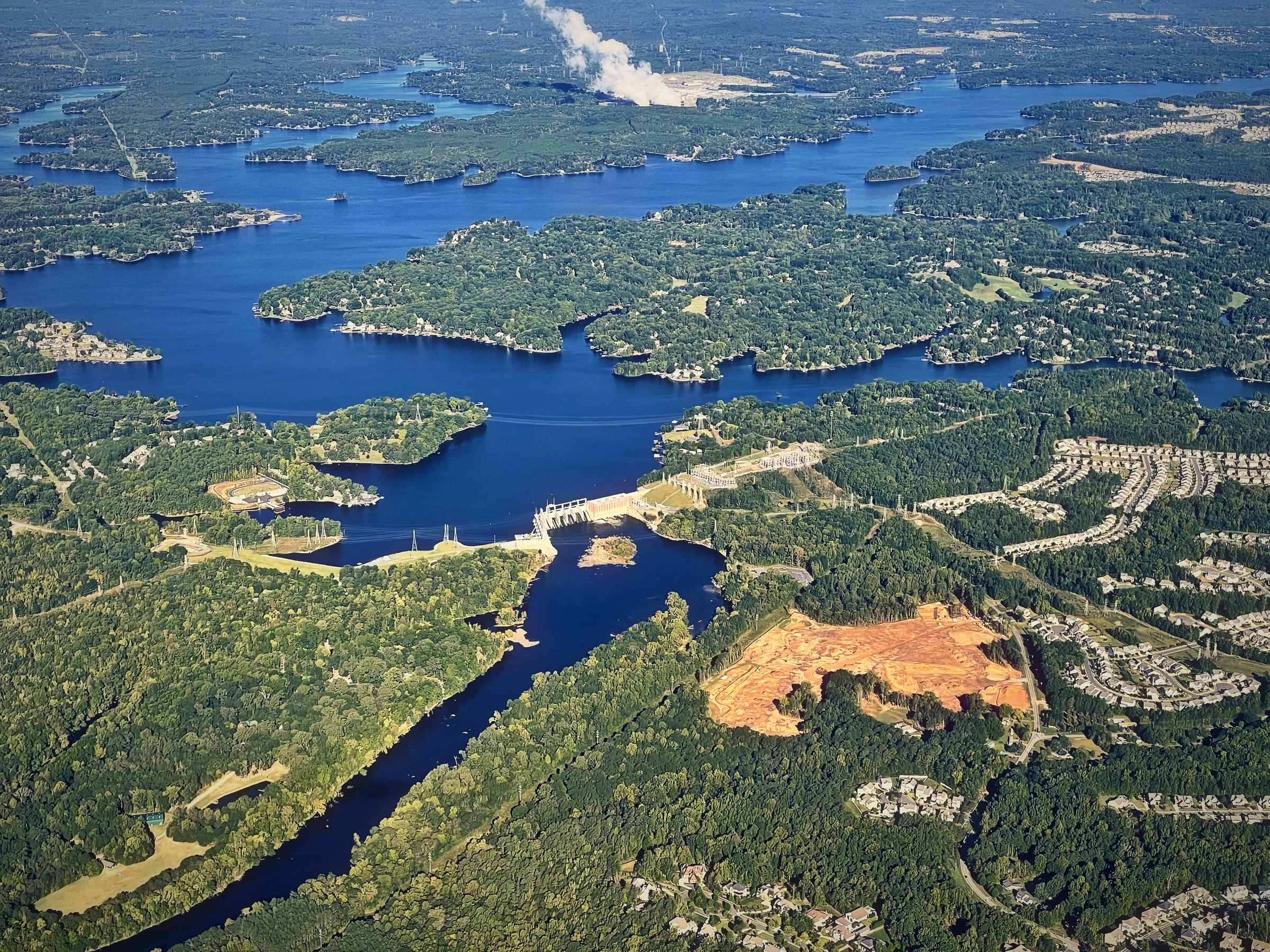 An aerial view of a reservoir branching like veins through green forest.
