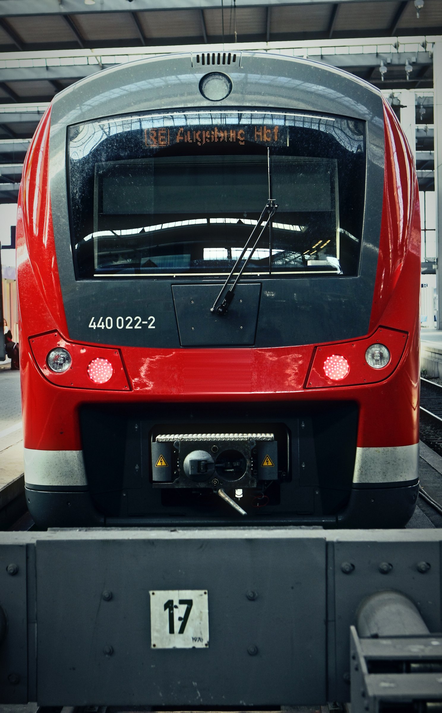 Red regional train cab facing the camera above a platform sign reading 17.