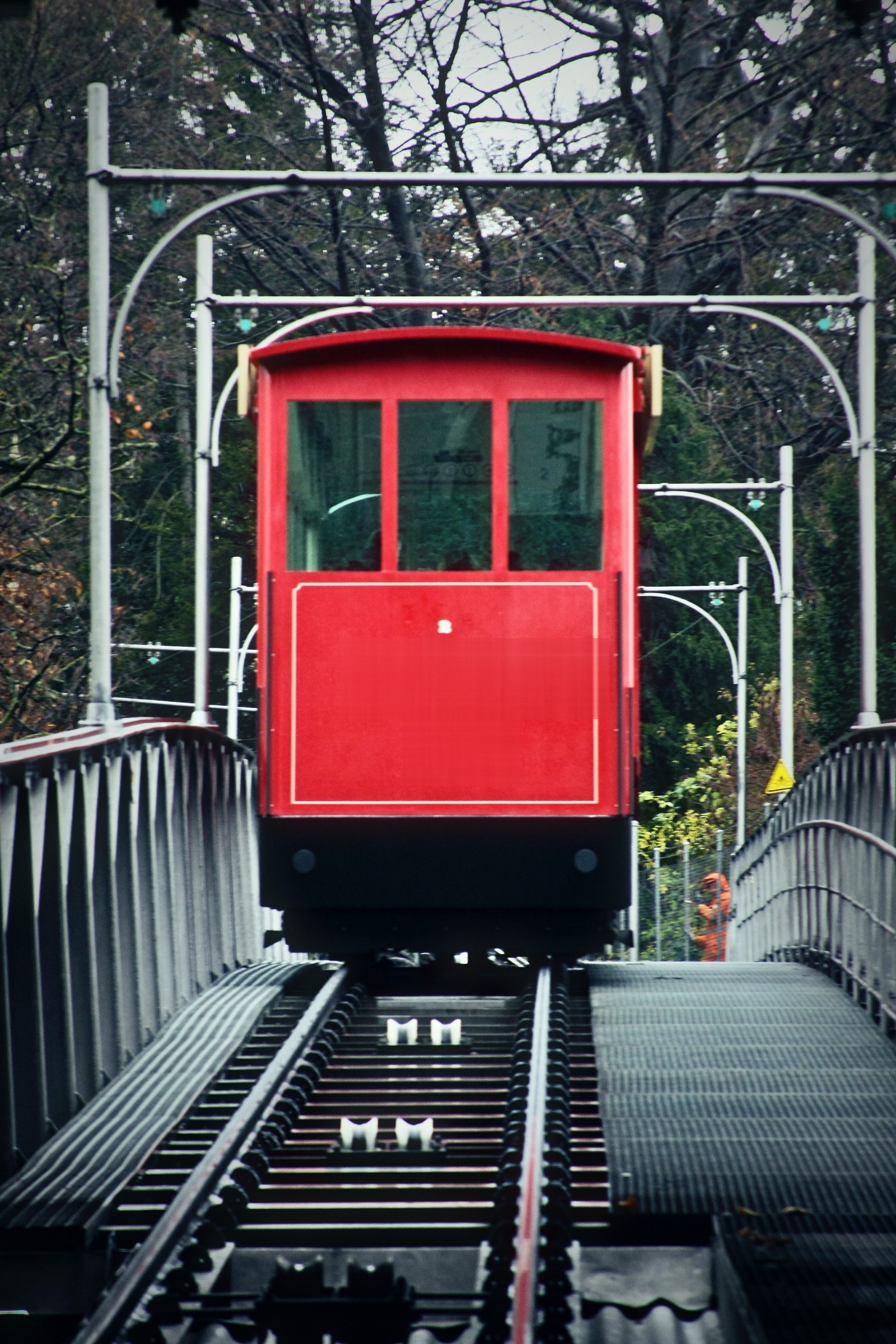 Small red funicular car on a steep track between metal railings.