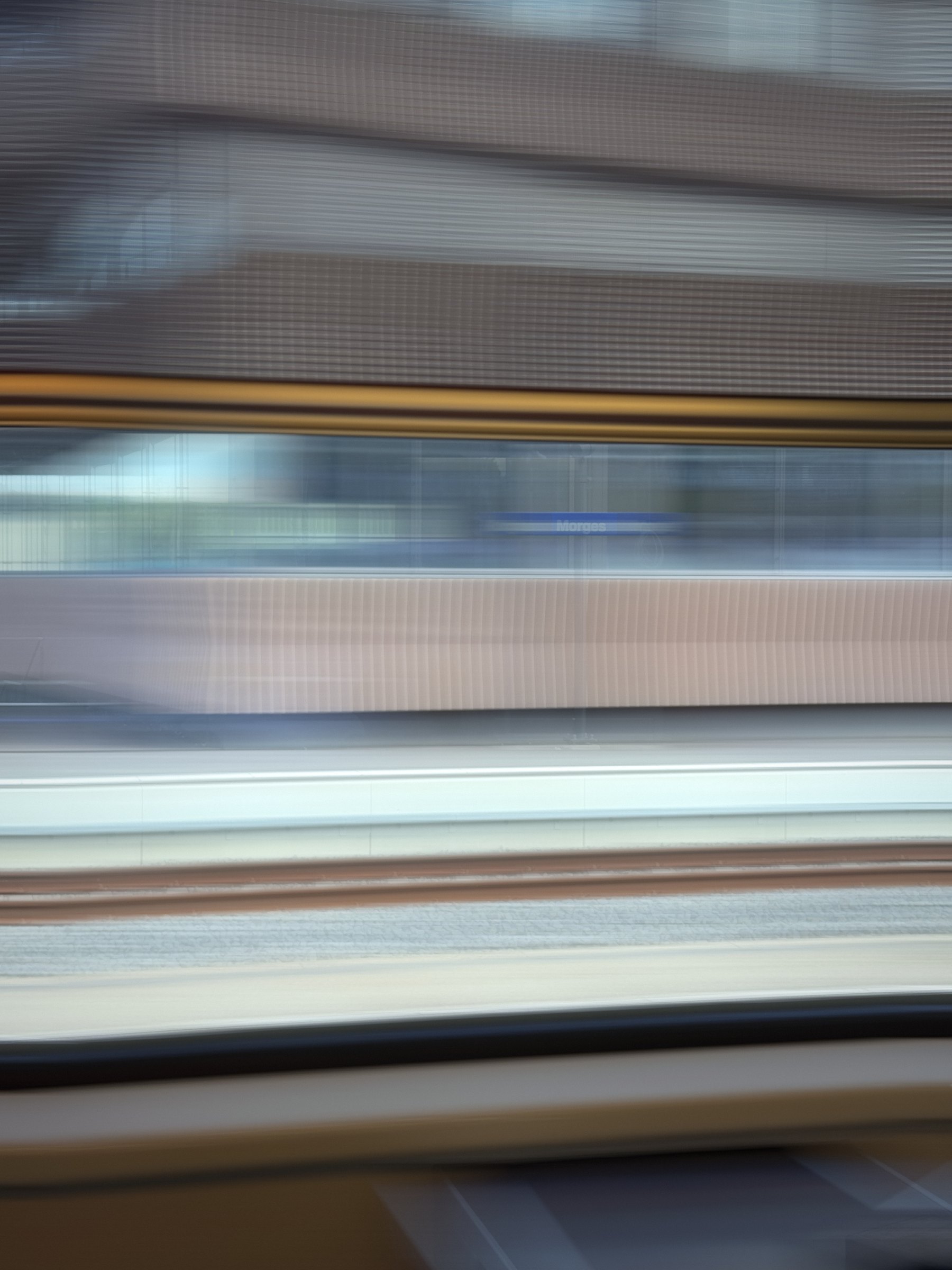 Horizontal streaks of grey, gold and blue from a moving train.