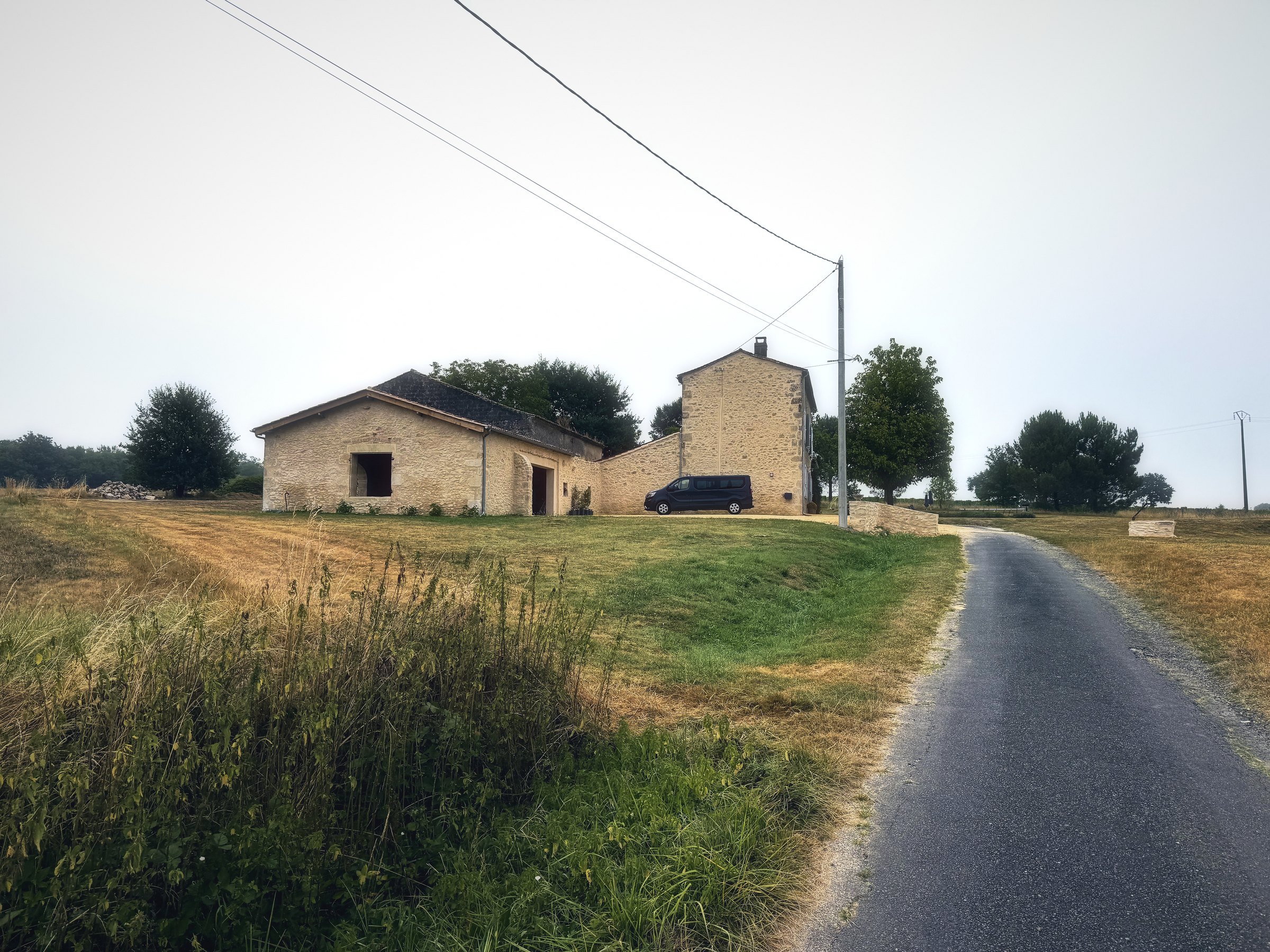 A stone farmhouse at the end of a narrow road, wrapped in soft morning mist.