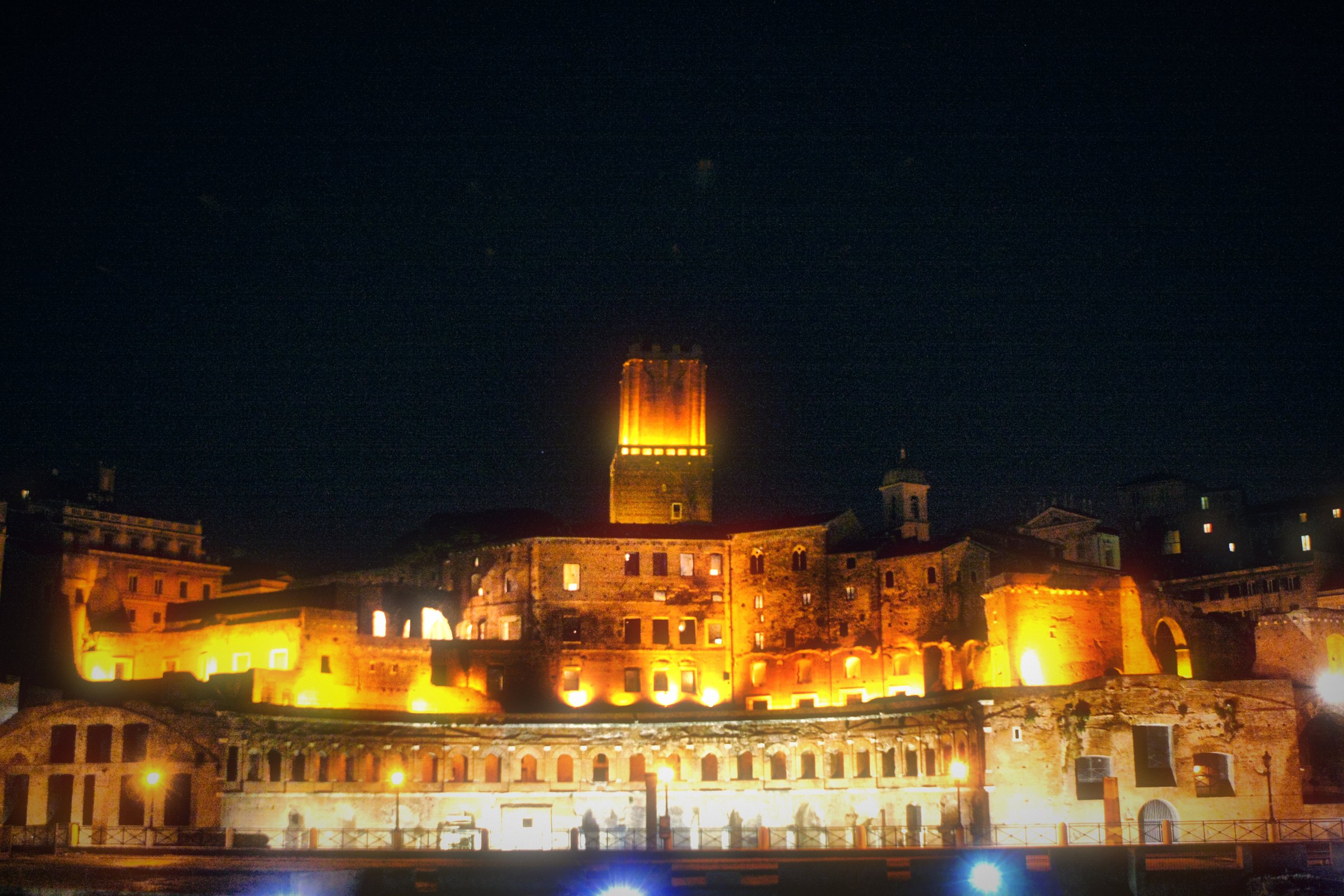 The forum and medieval tower lit gold against the night.