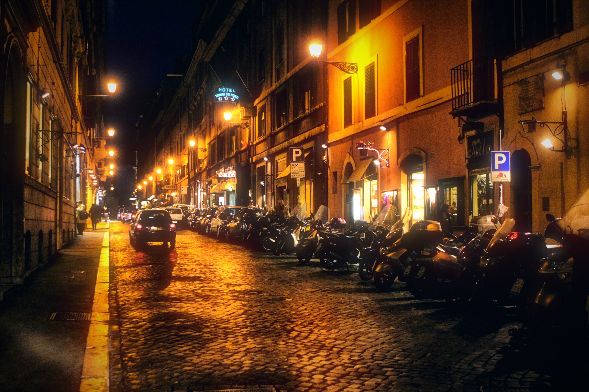 A wet Roman street at night, its cobbles glowing gold.