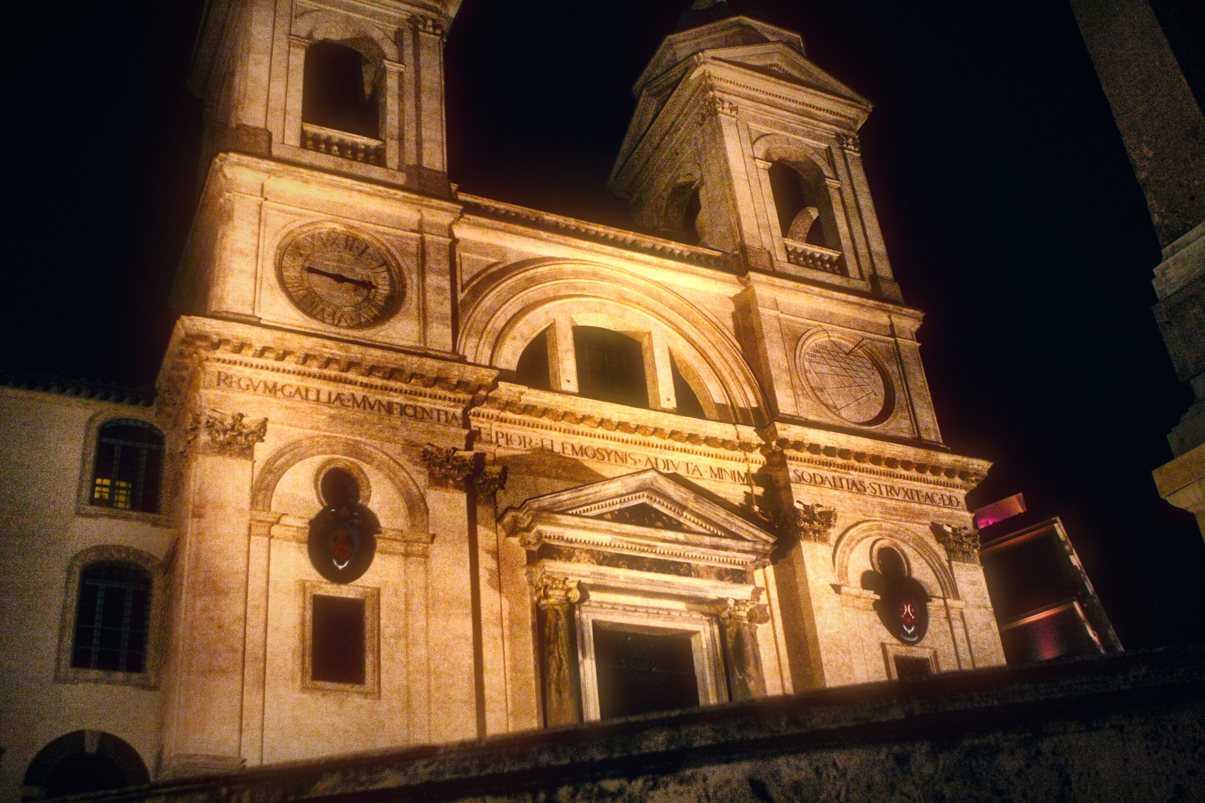 A white church facade with twin towers lit against the night.