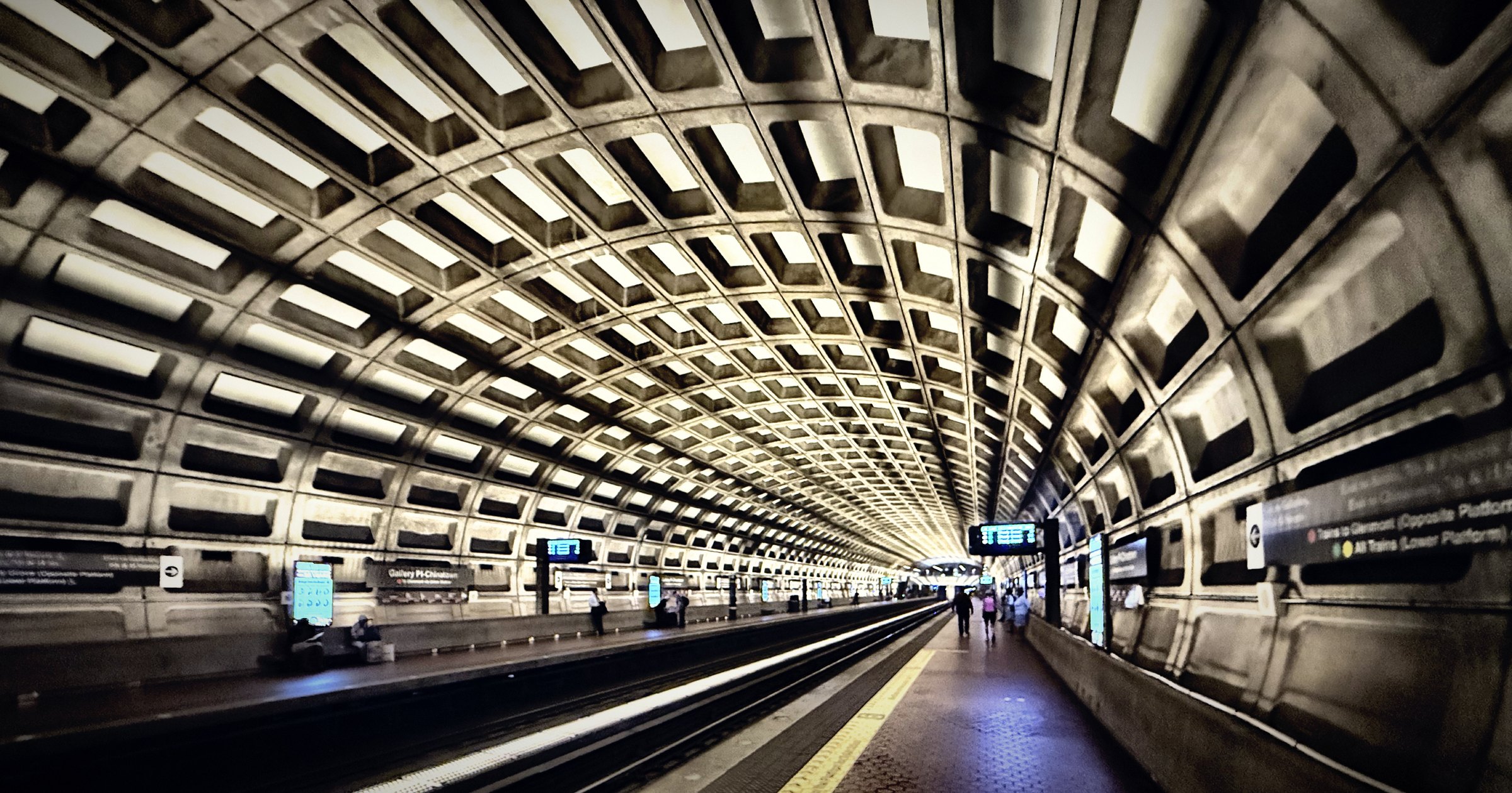 The coffered concrete vault of a subway station receding to a vanishing point.