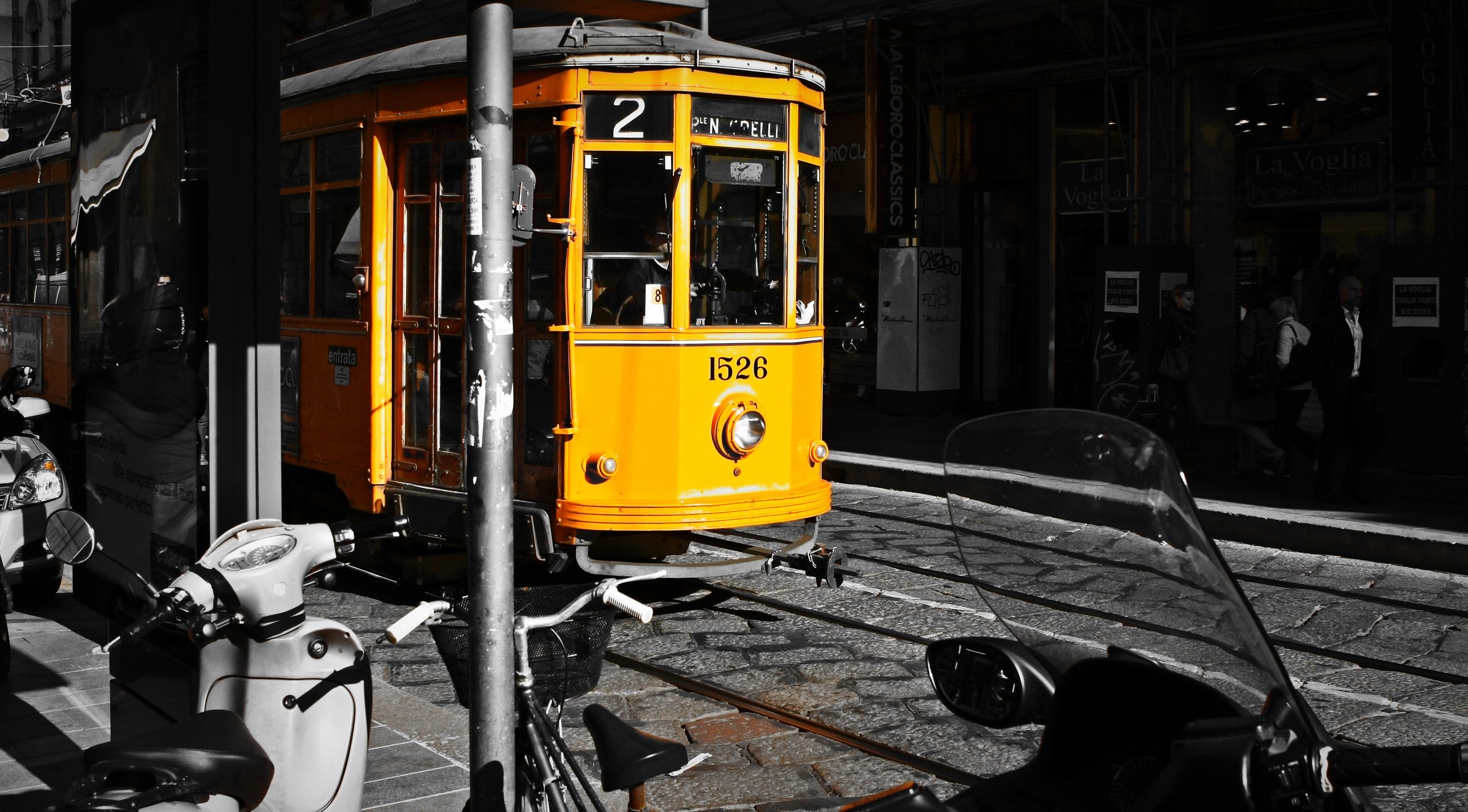 Black and white street scene with one yellow vintage tram in full colour.