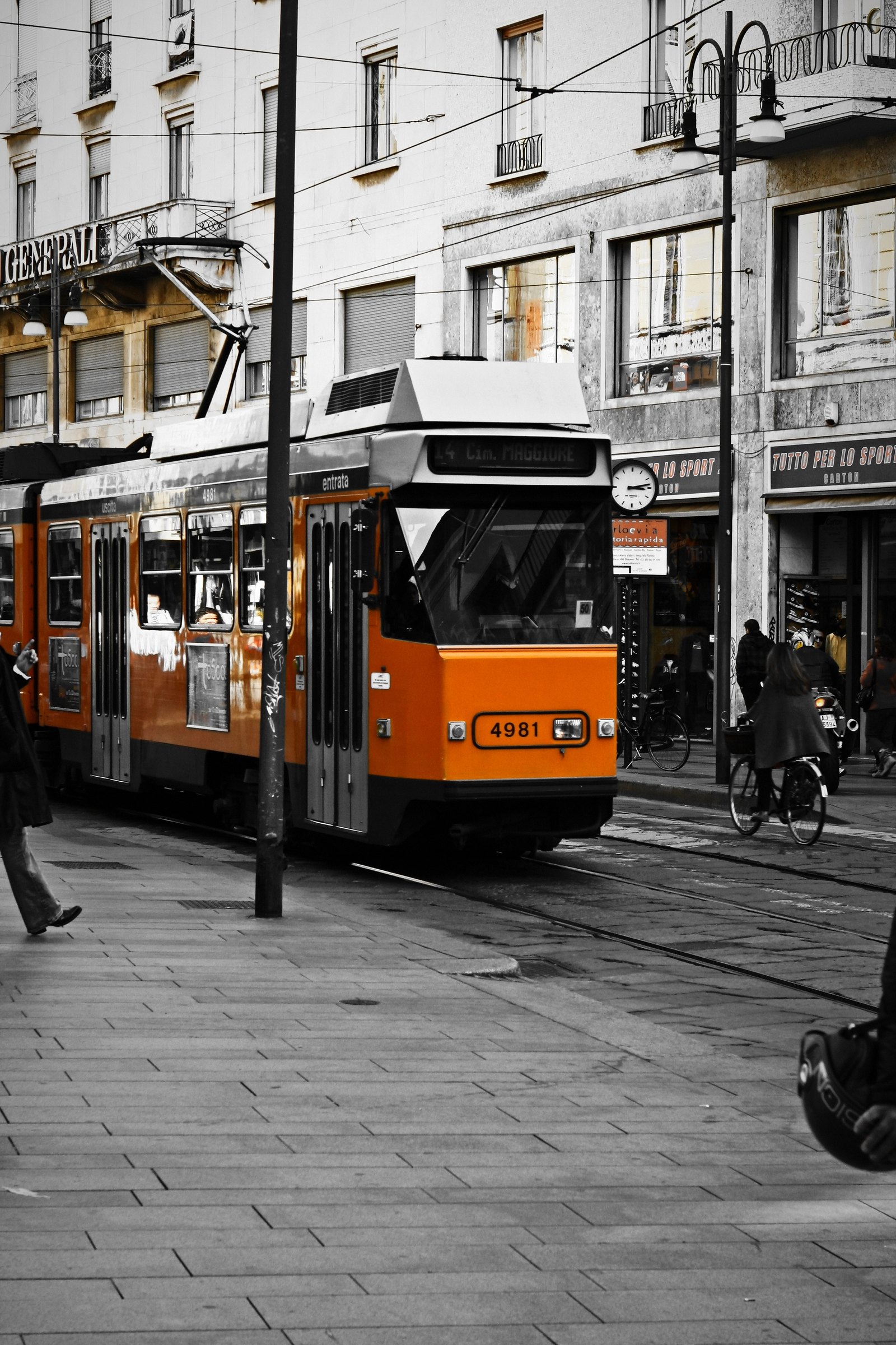 Black and white city corner with an orange tram kept in colour.