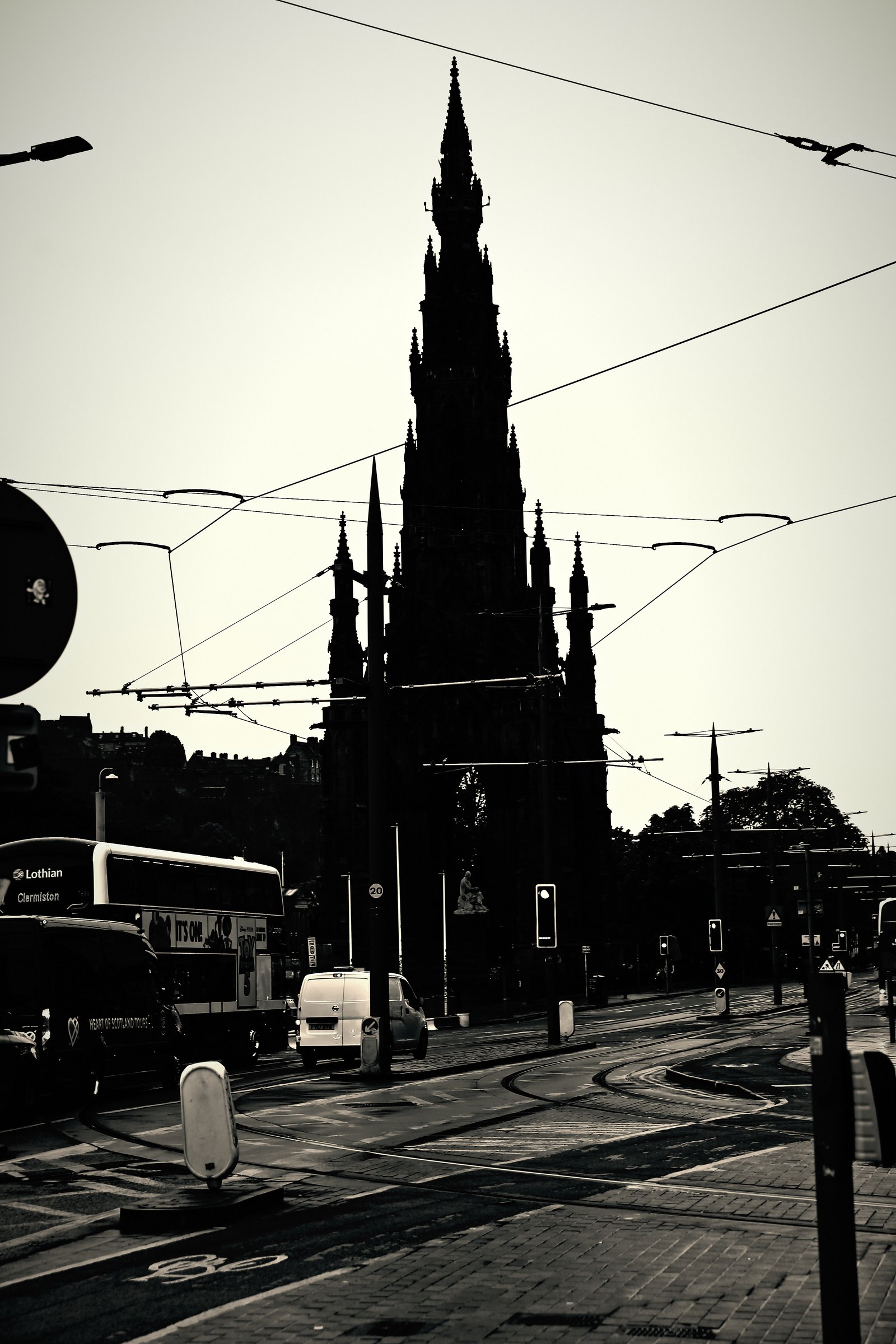 High-contrast silhouette of a Gothic spire crossed by tram wires.