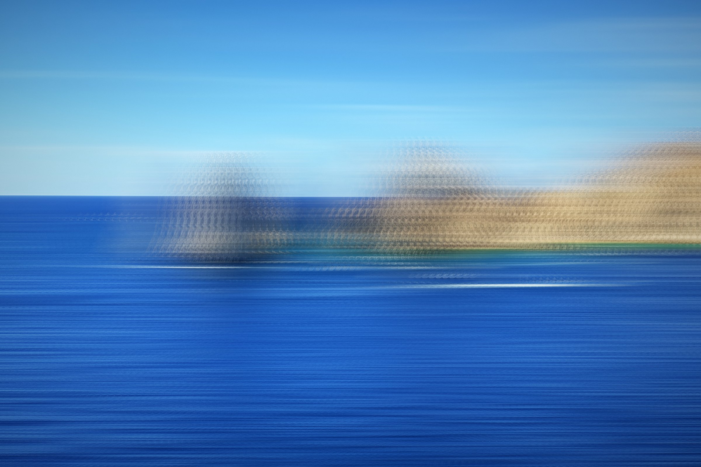 Sweeping horizontal bands of blue sea with distant pale rocks.