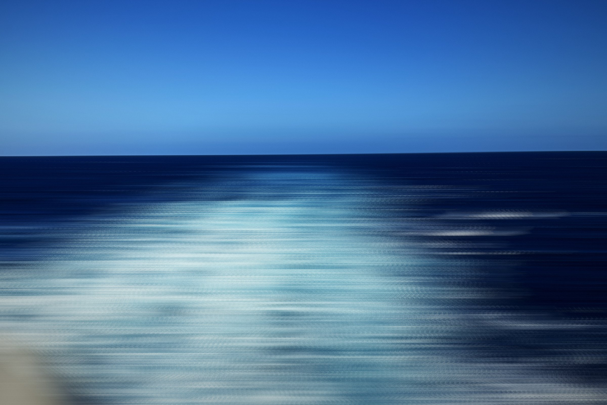 Horizontal streaks of white foam on deep blue water.
