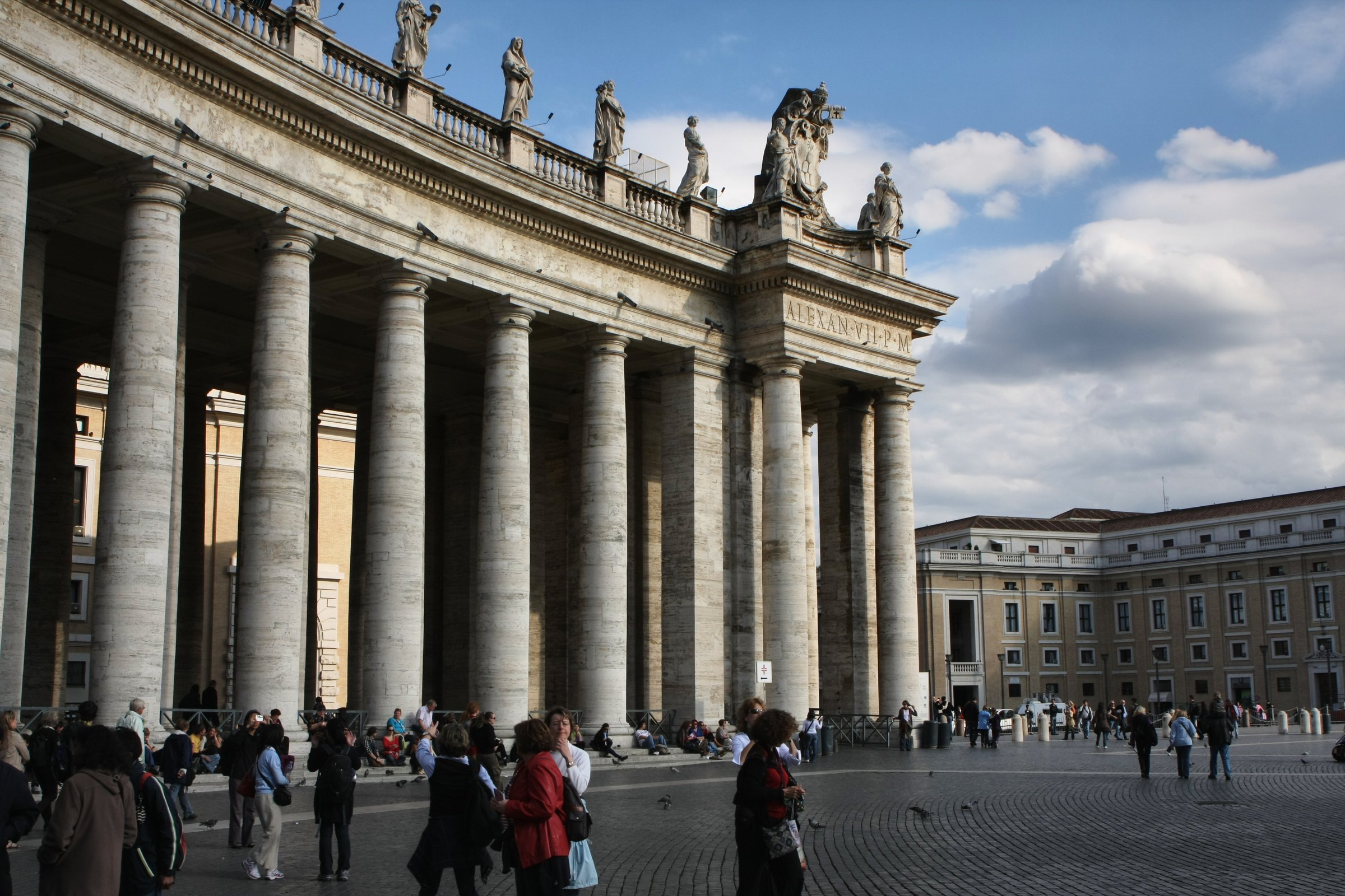 Bernini's colonnade at St Peter's Square with people walking past.