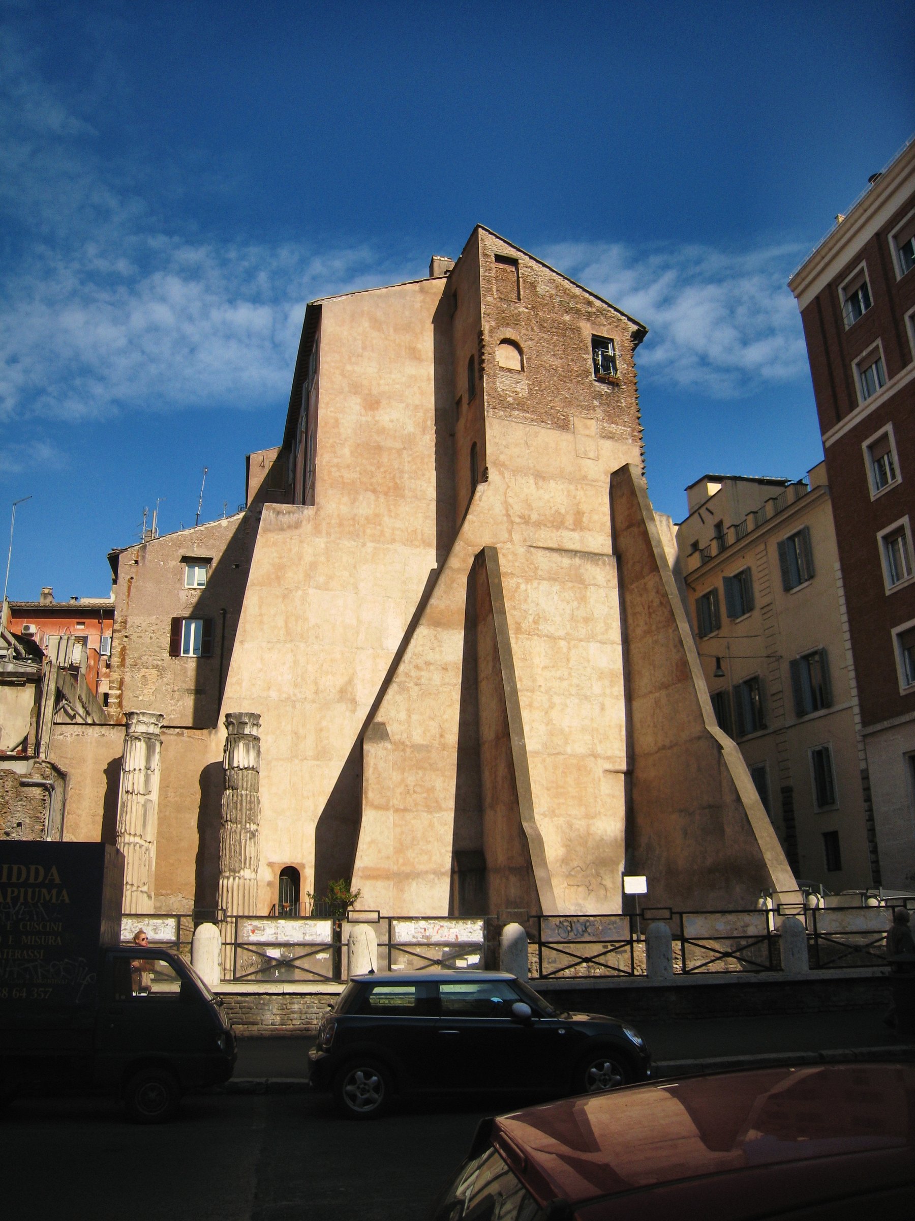 A tall brick ruin against a deep blue sky with a street below.