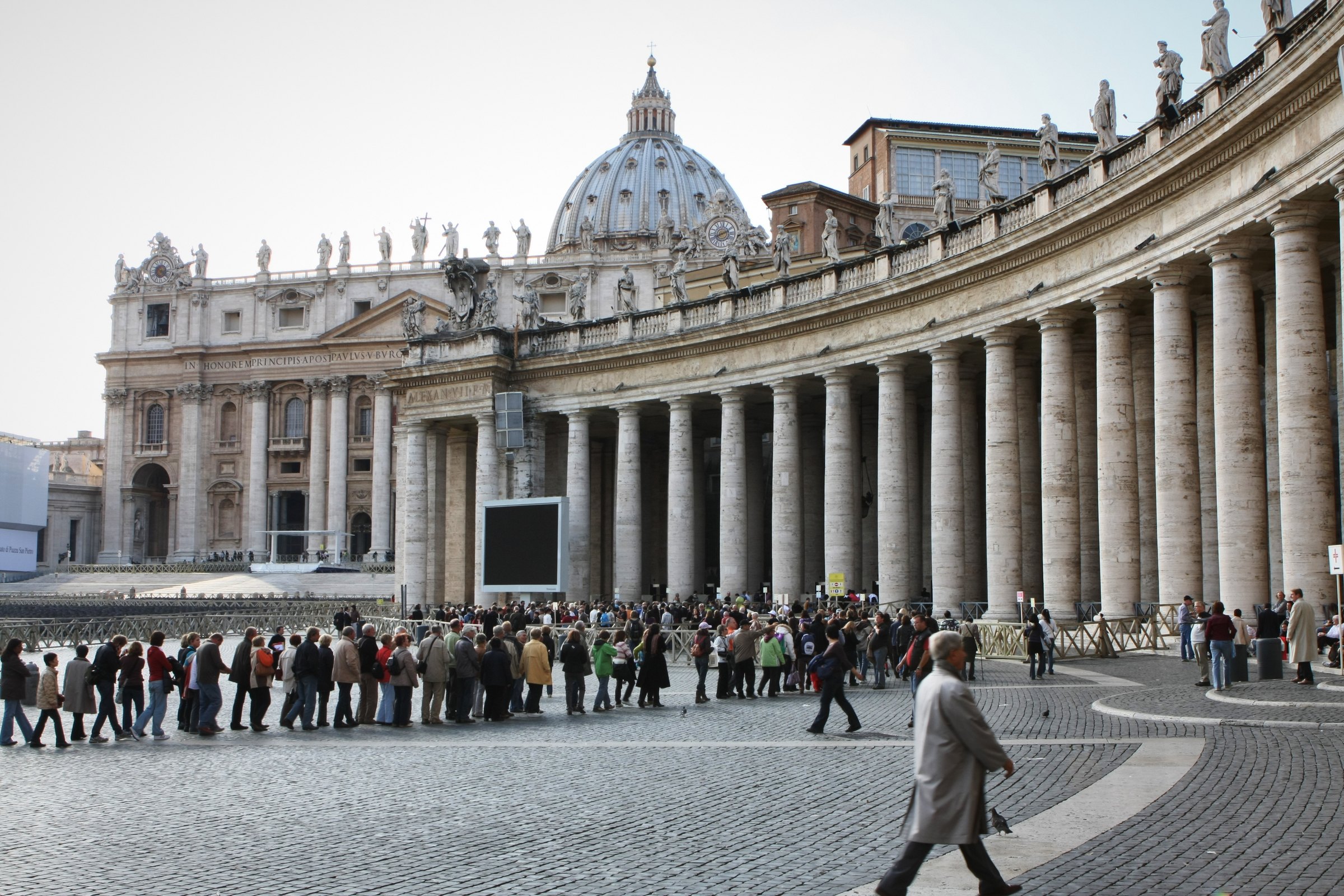 St Peter's Basilica and colonnade with a queue across the square.