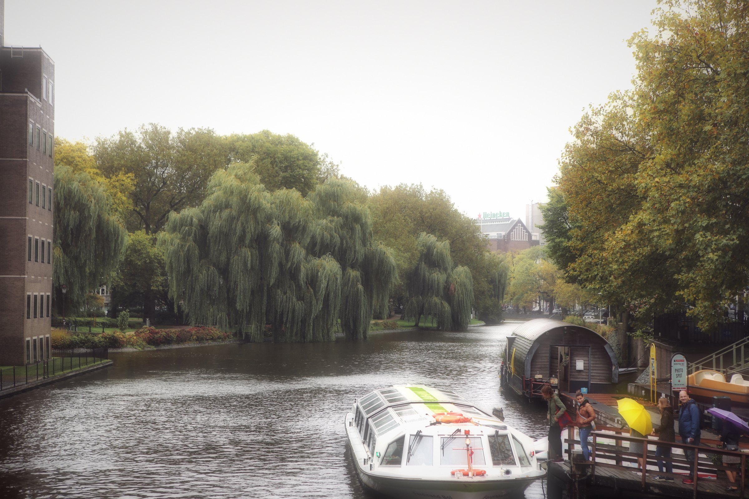 Weeping willows bending over a canal with a small boat passing.
