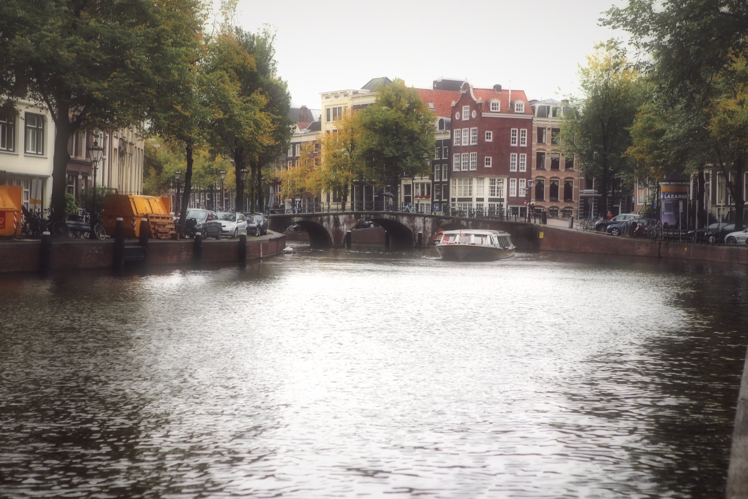 Sunlight glaring off a canal toward bridges and gabled houses.