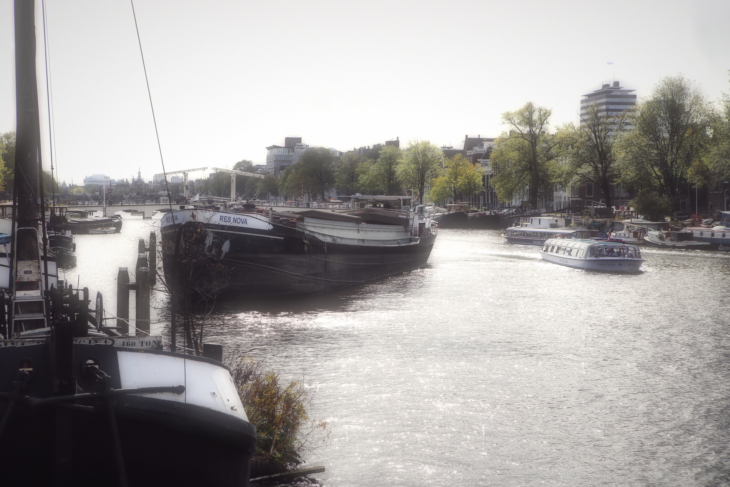 Old barges moored along a river under a pale sky.