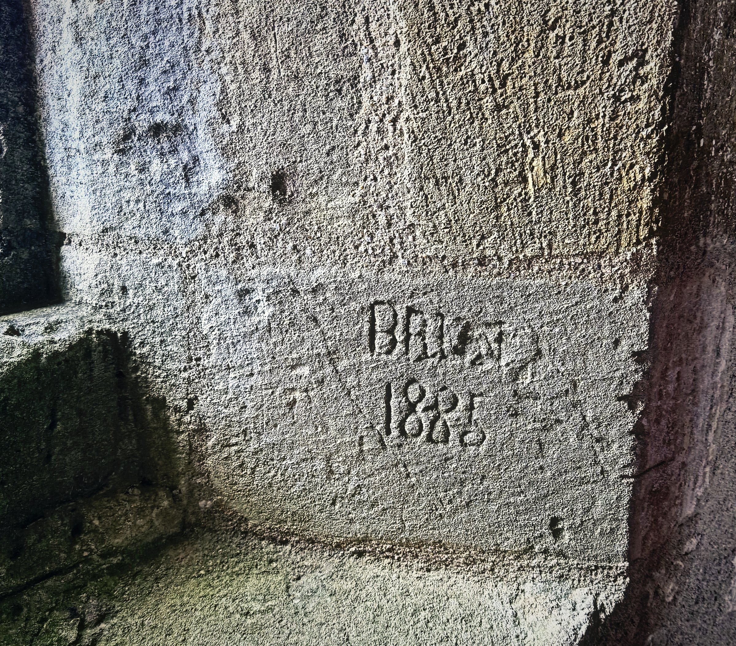 A name and date scratched into a limestone window seat inside a castle tower.