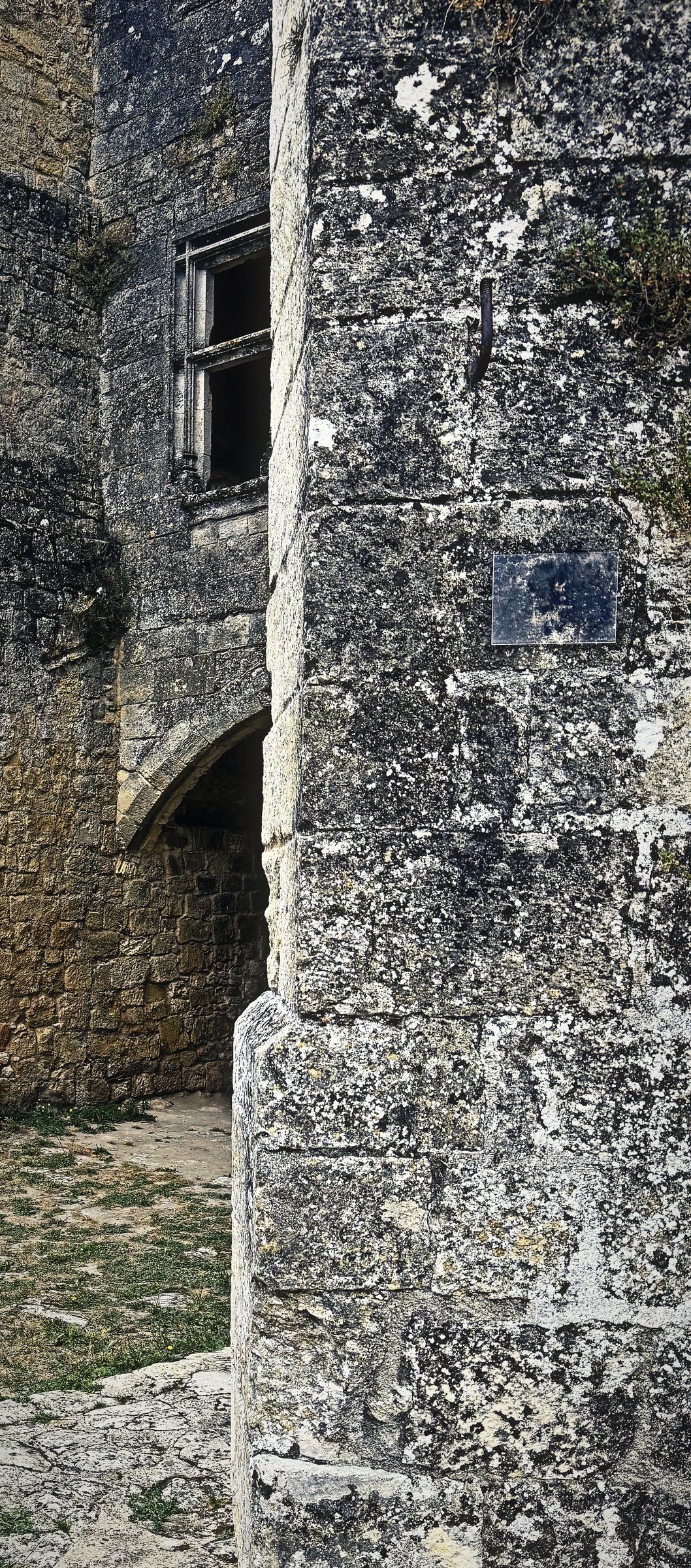 A tall weathered stone pillar of a castle ruin standing against a pale sky.