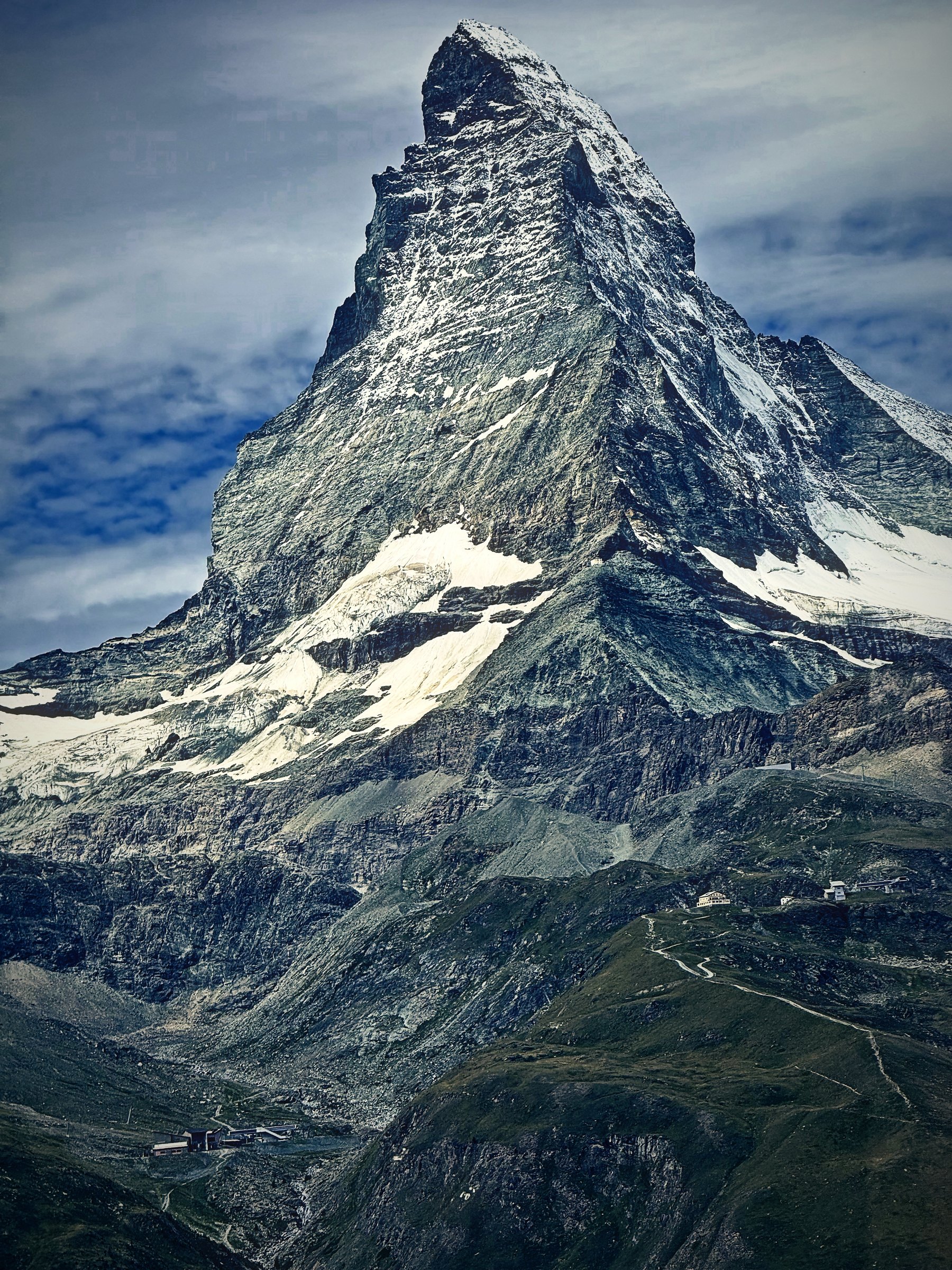 Close view of the Matterhorn's rock face streaked with snow under a pale sky.