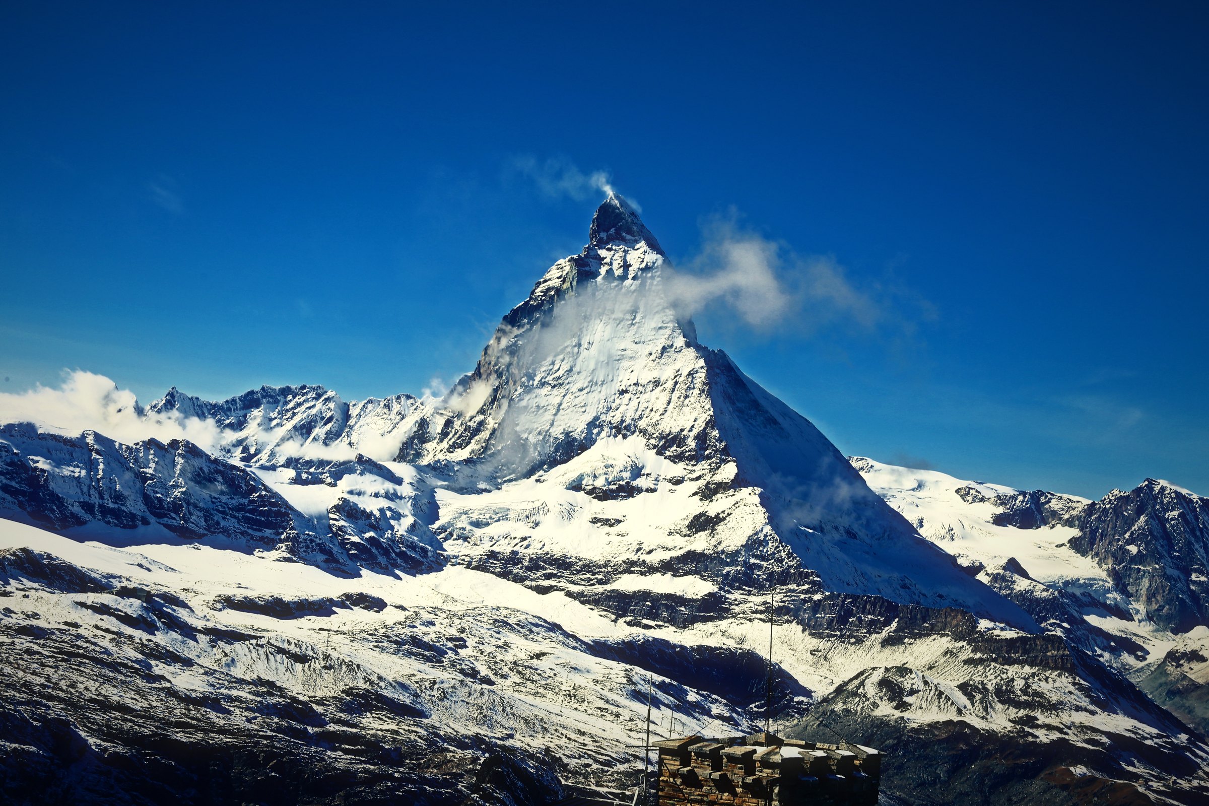 The snowy Matterhorn above wide snowfields under a deep blue sky.