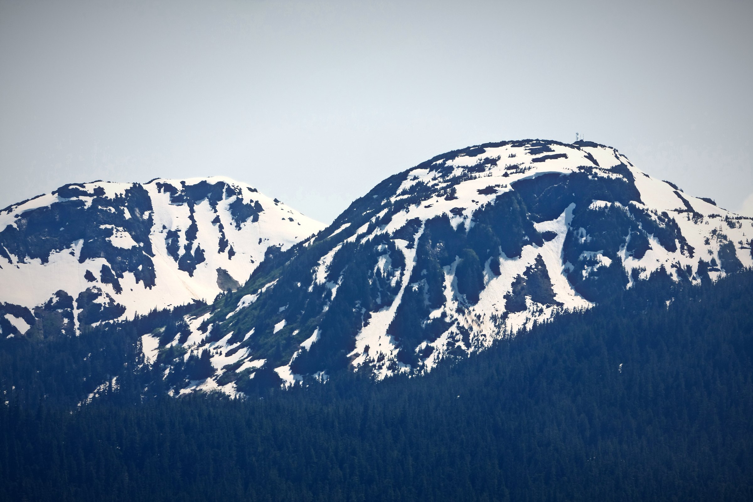 Two snowy mountain ridges side by side under a pale sky.